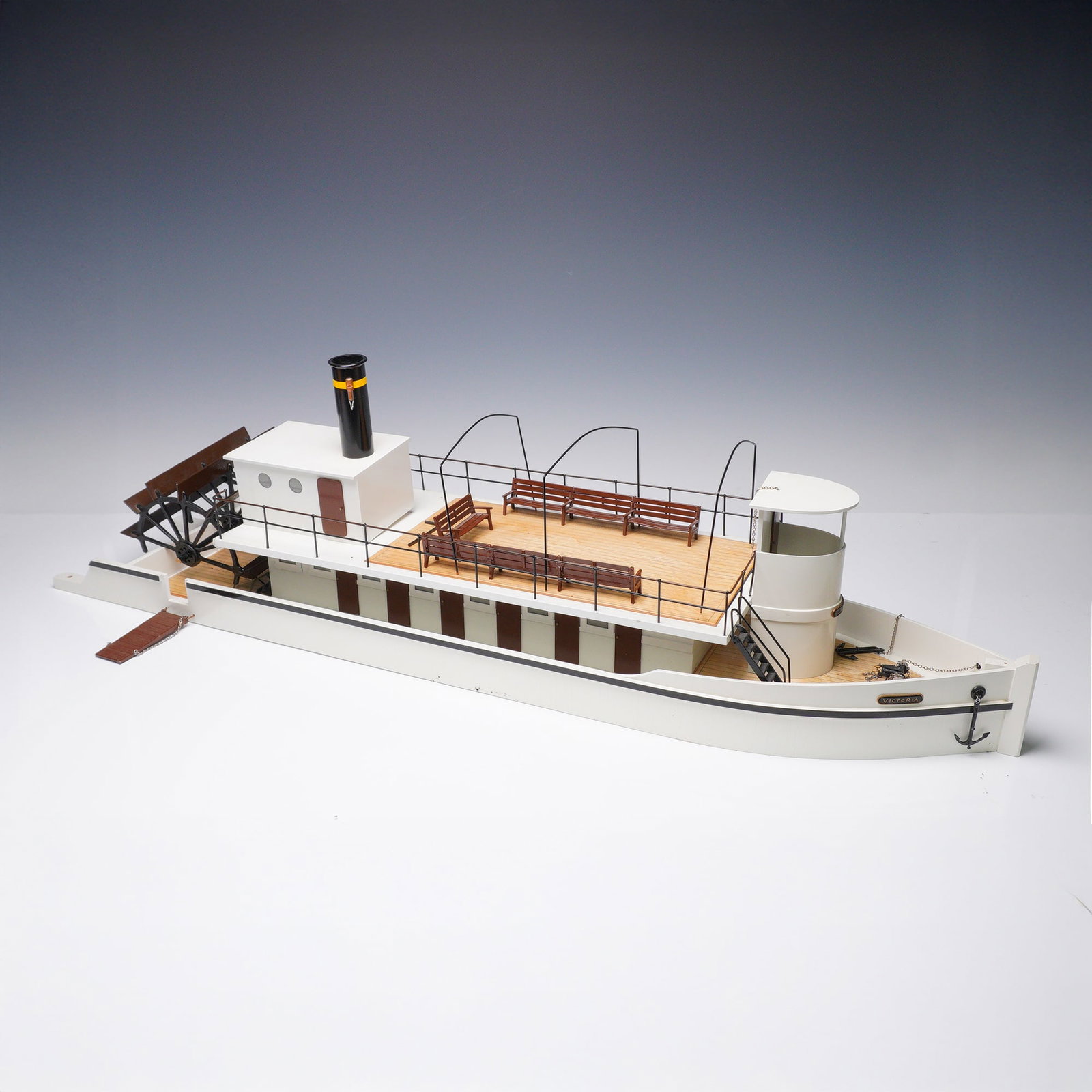 Model Toy Paddle Steamer - Victoria: A detailed and well-crafted scale model of a paddle steamer named Victoria, constructed with painted wood and metal components. The model features a twin-deck design with open passenger benches on the