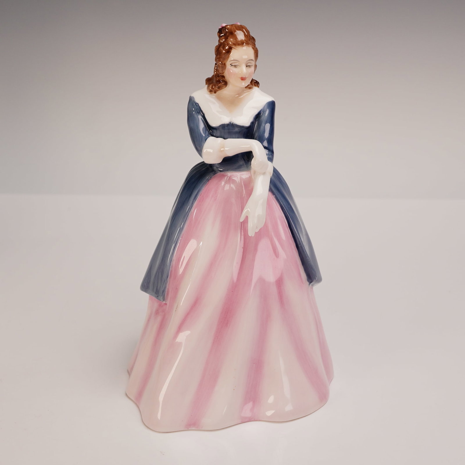 Royal Doulton Figurine Maxine HN3199: Royal Doulton bone china figurine Maxine HN3199, designed by A. Hughes. This refined piece features a poised young woman in a flowing pink and white gown with a deep blue bodice and white shawl collar