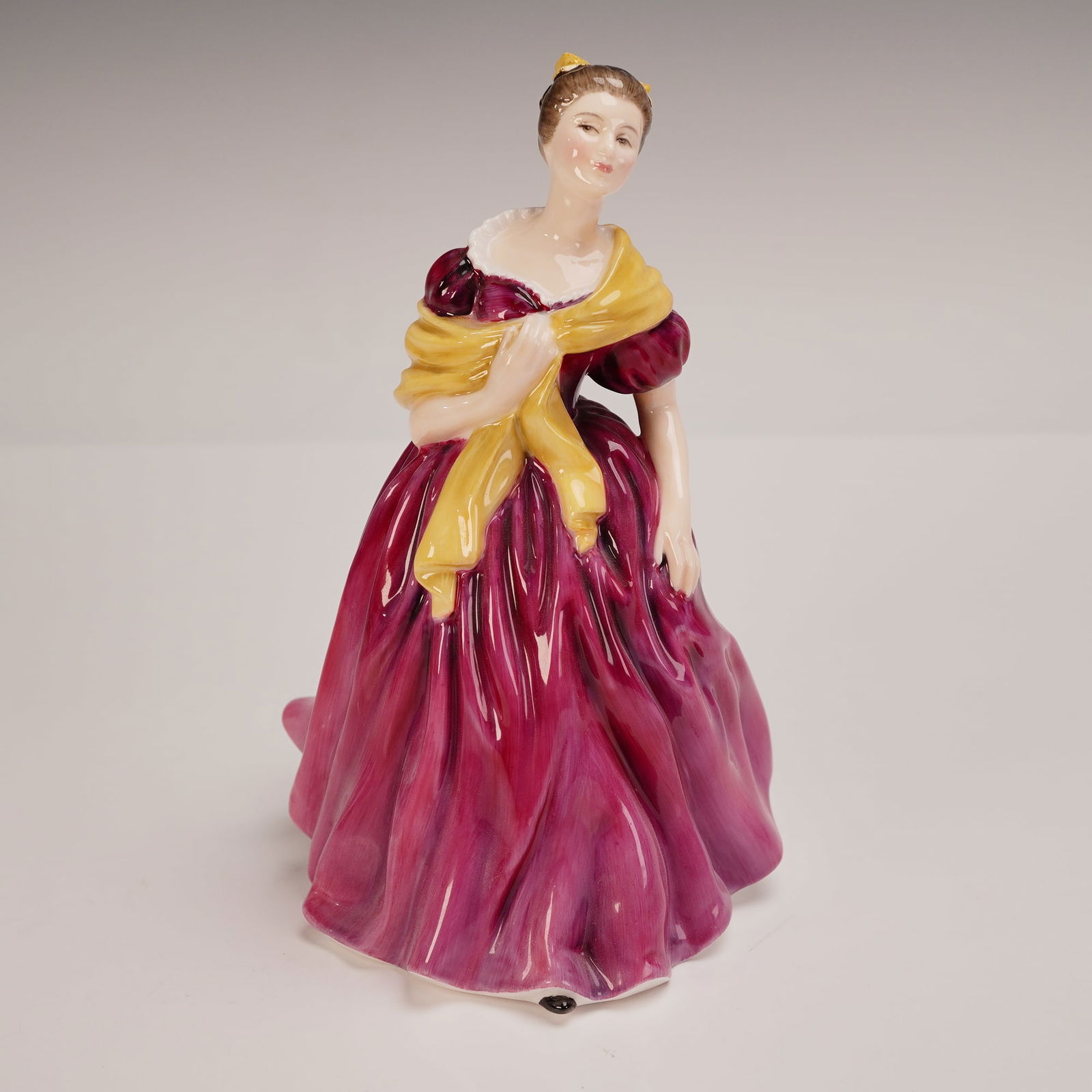 Royal Doulton Figurine, Adrienne HN2152: Charming Royal Doulton figurine titled Adrienne, HN2152, modeled by Peggy Davies and issued in 1957. This elegant hand-painted figure features a young woman in a sweeping mulberry gown with puffed sle