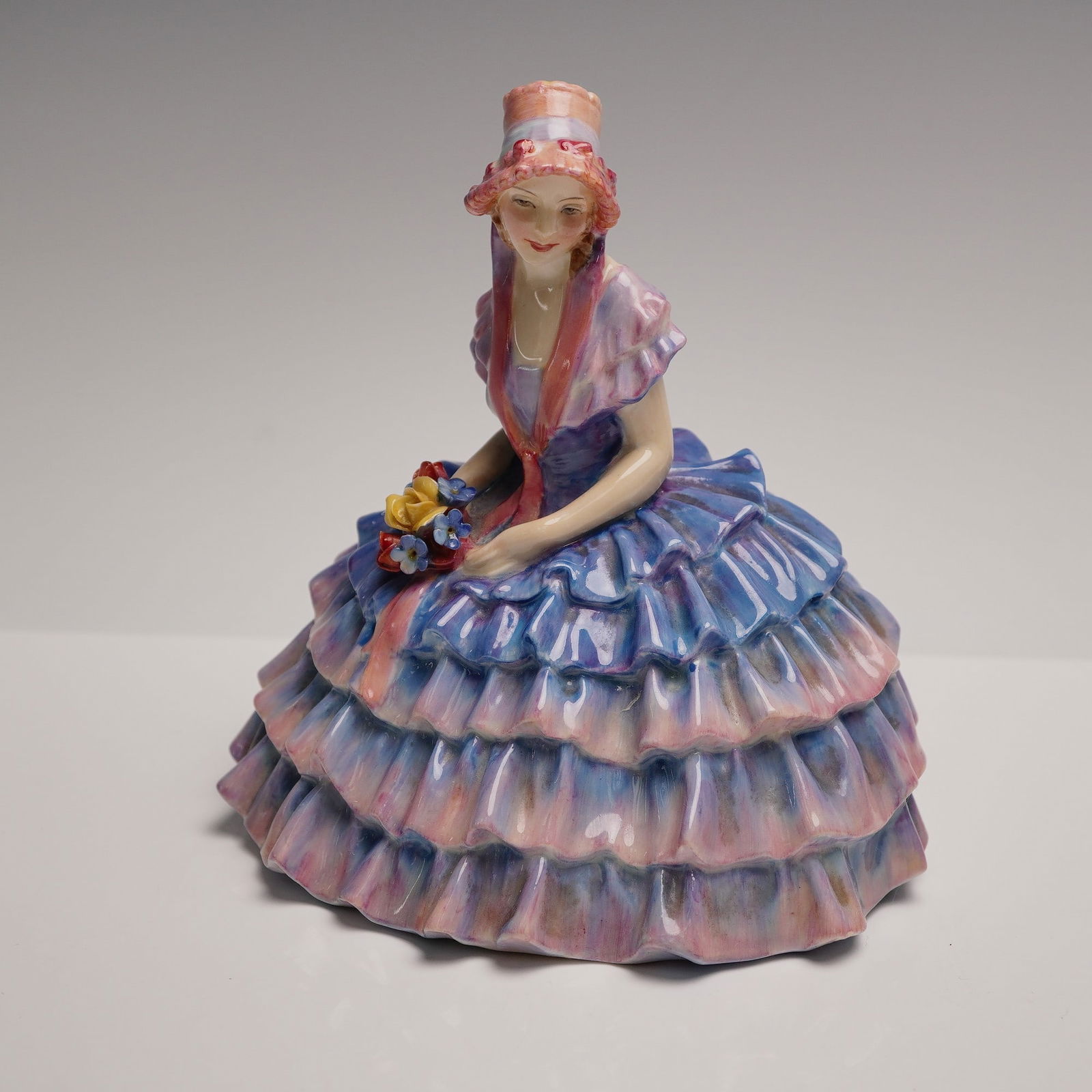 Royal Doulton Figurine, Chloe HN1765: A graceful Royal Doulton porcelain figurine titled Chloe, model HN1765, designed by Leslie Harradine and first introduced in the 1930s. The seated young woman wears an elegant multi-tiered crinoline g