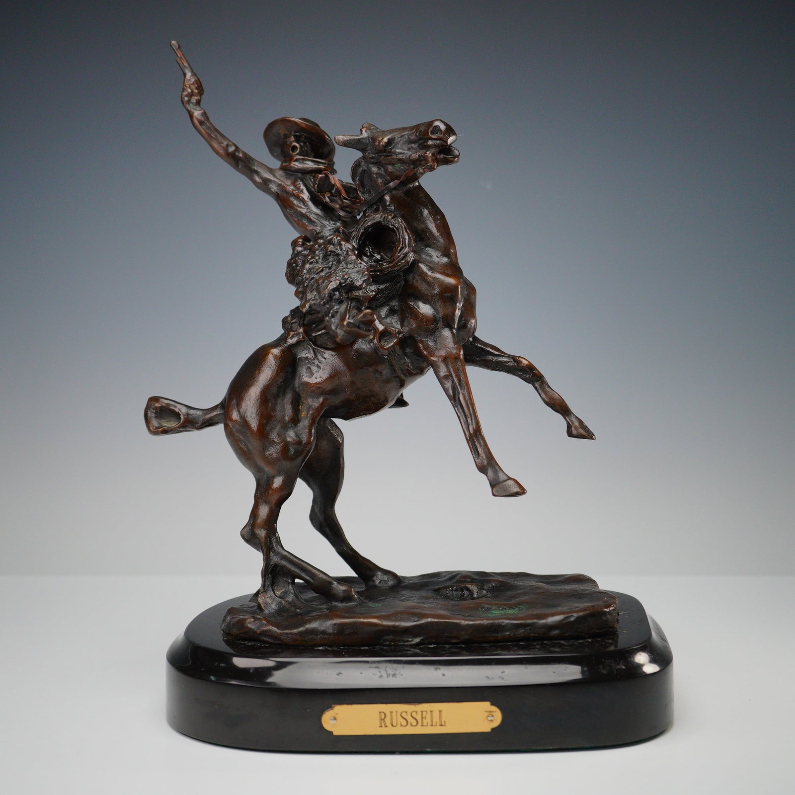 After C.M. Russell, Bronze Sculpture, Smokin' Up: A finely cast bronze sculpture after Charles Marion Russell (American, 1864-1926), titled Smokin' Up. The dynamic composition captures a cowboy mid-action on a rearing horse, firing a pistol into the 
