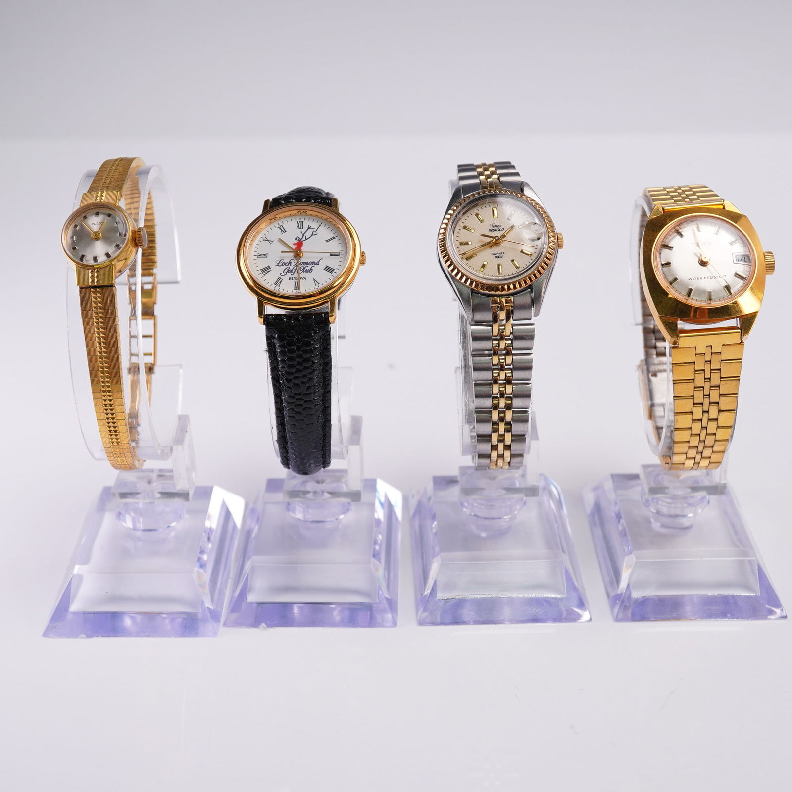 4pc Ladies' Watch Lot Timex Bulova Pulsar Gold Tone: Lot of four vintage and modern ladies' wristwatches including a gold-tone Timex with date display, a Bulova Loch Lomond Golf Club quartz with black leather strap, a two-tone Timex Indiglo quartz with