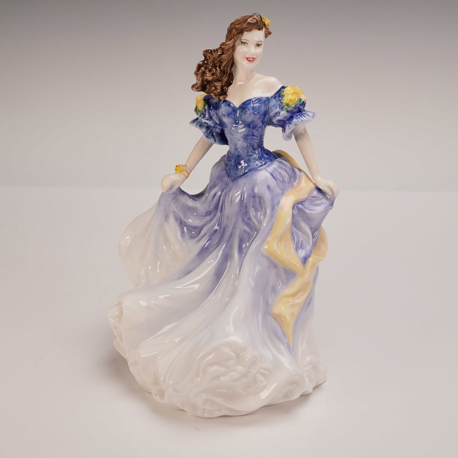 Royal Doulton Figurine, Rebecca HN4041: Royal Doulton bone china figurine designated as the Figure of the Year for 1998. Features a hand-decorated figure of a woman in a flowing blue and white gown with yellow floral accents and ribbon. The