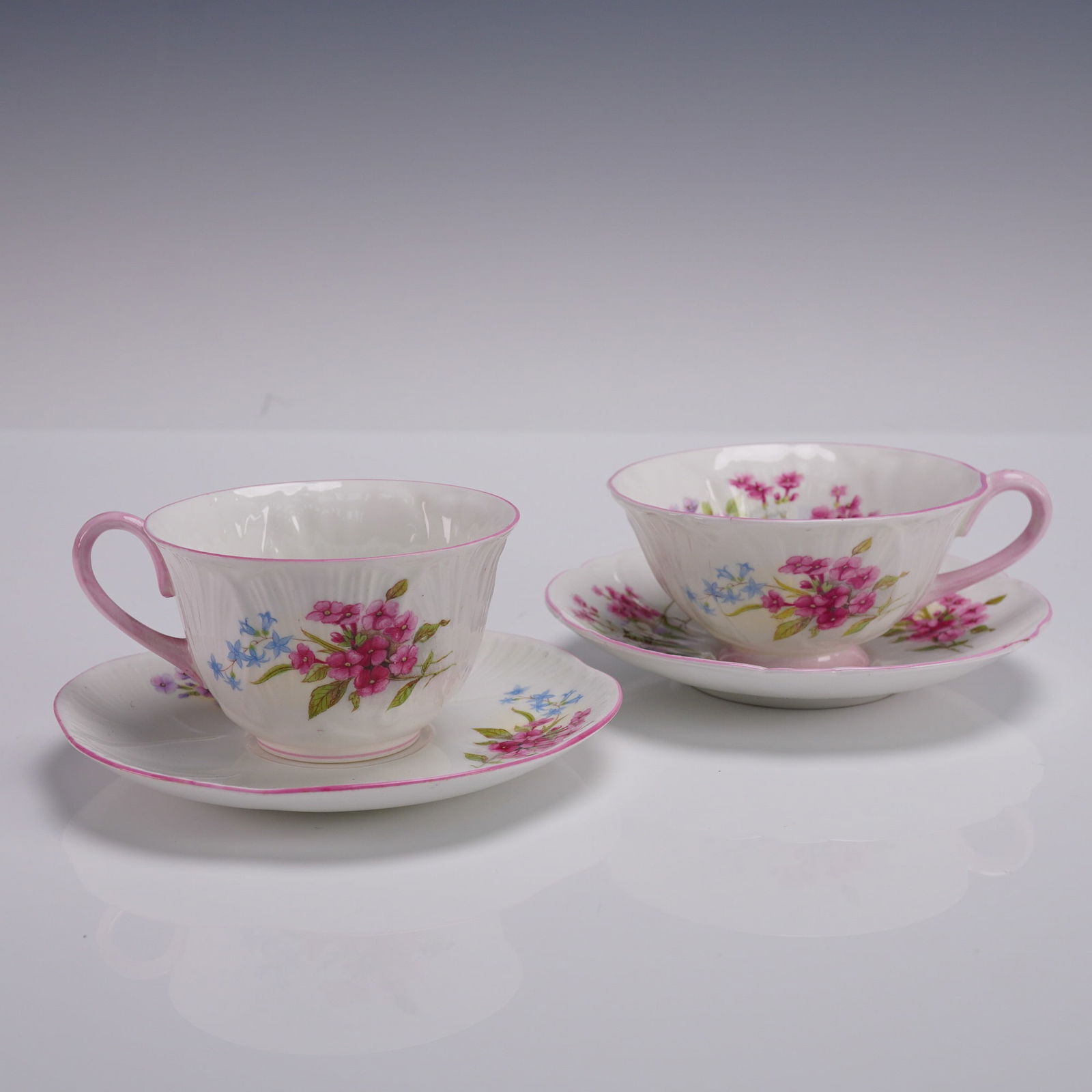 4pc Shelley Fine Bone China Tea Cups and Saucers, Stocks Pink: A dainty 4-piece Shelley bone china tea set in the Oleander shape, decorated in the vibrant Stocks Pink pattern. Each piece features scalloped edges with hand-applied pink trim, soft fluted ribbing, a