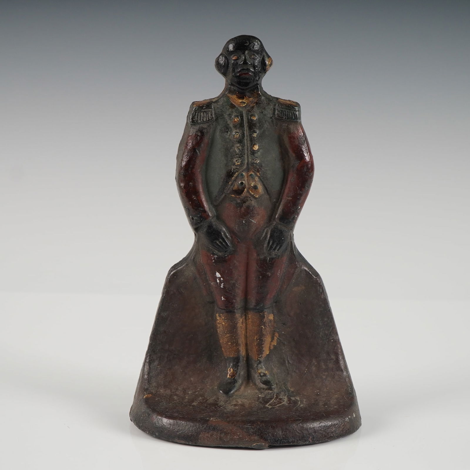 Antique Black Americana Butler Cast Iron Figural Doorstop: A painted cast iron figural doorstop depicting a butler dressed in 18th century attire. Retains traces of the original hand-painted polychrome finish in red, gold, and green. Flat-backed form with sem