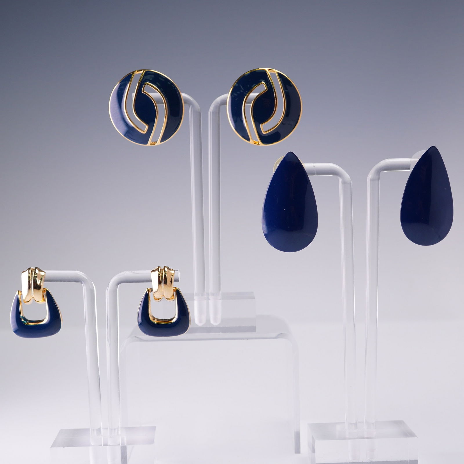 3 Pair Ladies Post Earrings Including Trifari Enamel Set: Lot of three pairs of ladies post-back earrings in bold gold tone and navy enamel styles. Includes round navy and gold interlock earrings marked Trifari, geometric gold and navy drops with open center