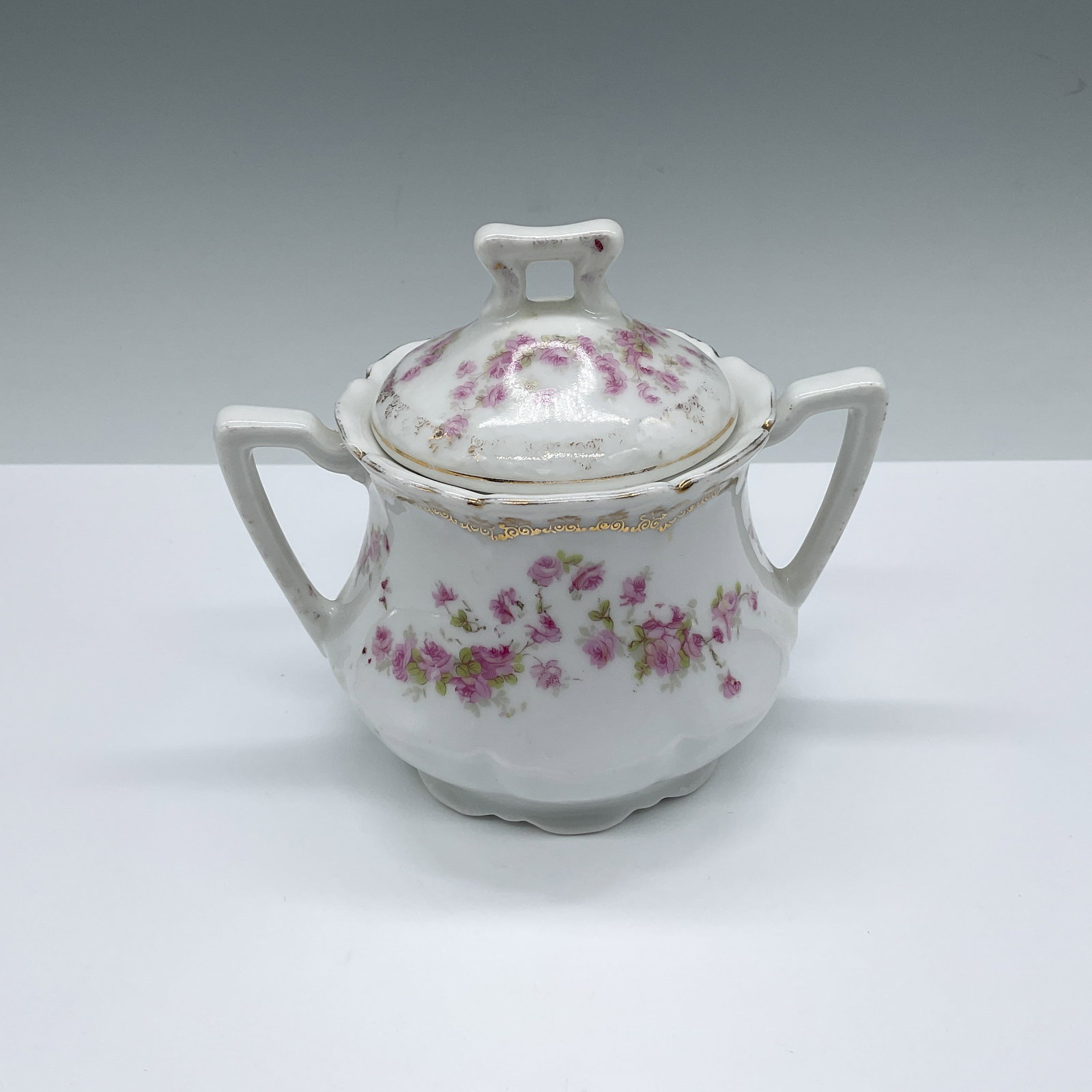 Vintage German Porcelain Floral Covered Sugar Bowl: A charming white double-handled sugar bowl adorned with cute pink roses, Marked Germany on the underside. Issued: 20th century Dimensions: 5.5"L x 4.25"W x 4.5"H Country of Origin: Germany