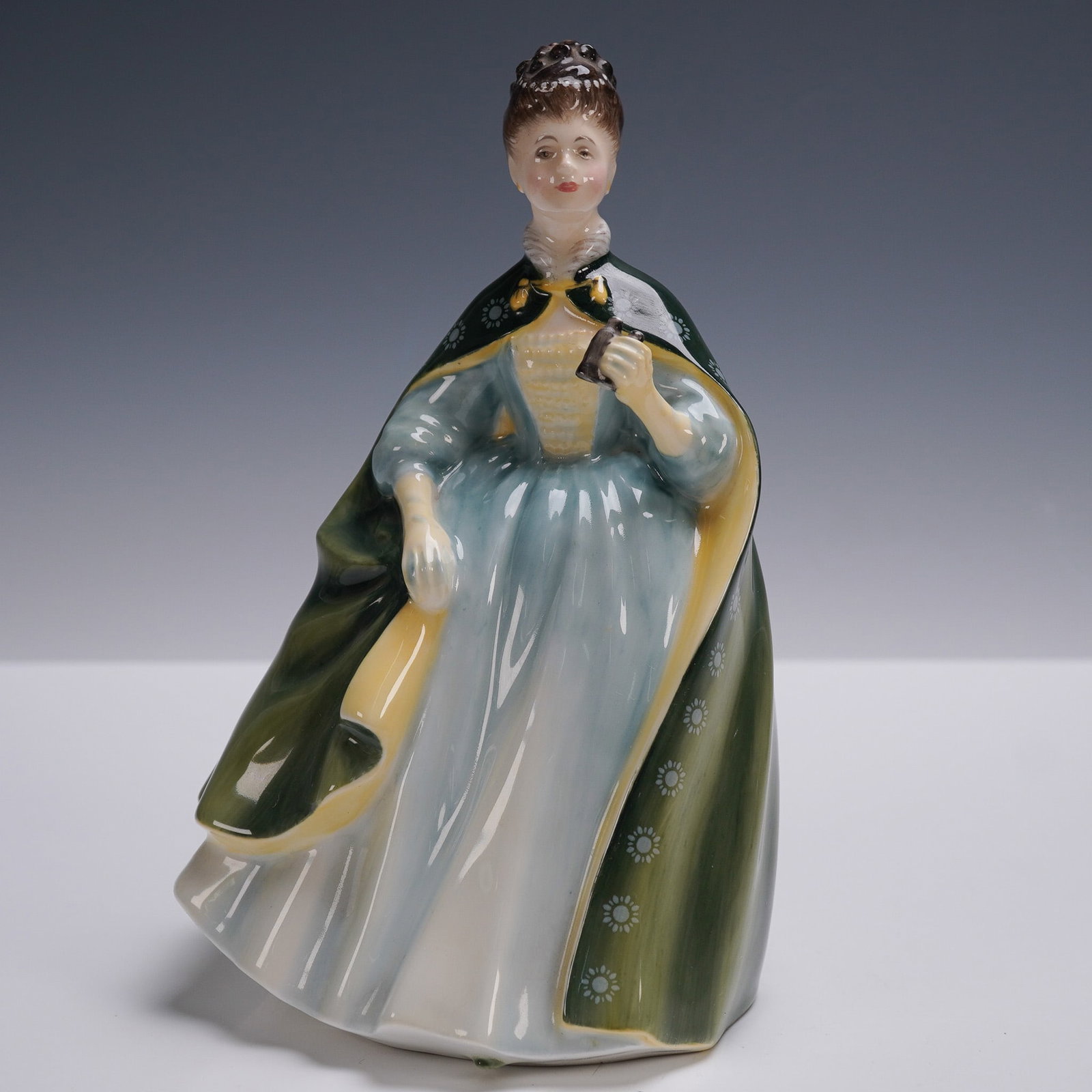 Royal Doulton Figurine, Premiere HN2343: This Royal Doulton bone china figurine is part of the Peggy Davies Classic series, it portrays a poised Victorian era lady dressed in a flowing blue and white gown with a moss green floral trimmed clo