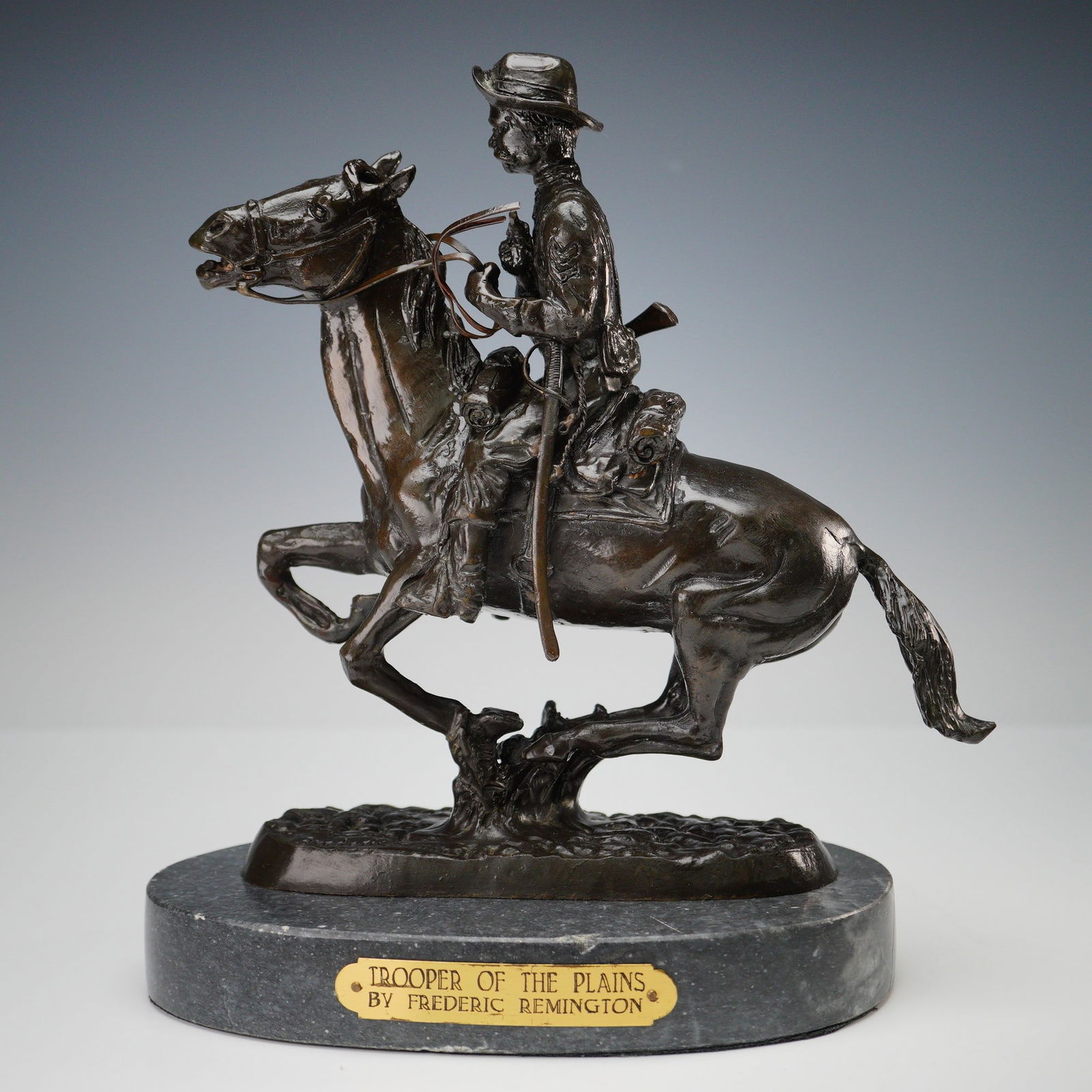 Frederic Remington Bronze Trooper of the Plains Sculpture on Marble Base: Bronze sculpture titled Trooper of the Plains by Frederic Remington, depicting a mounted cavalryman in full uniform with reins and rifle, mid-charge on horseback. Rich with period detail and dynamic m
