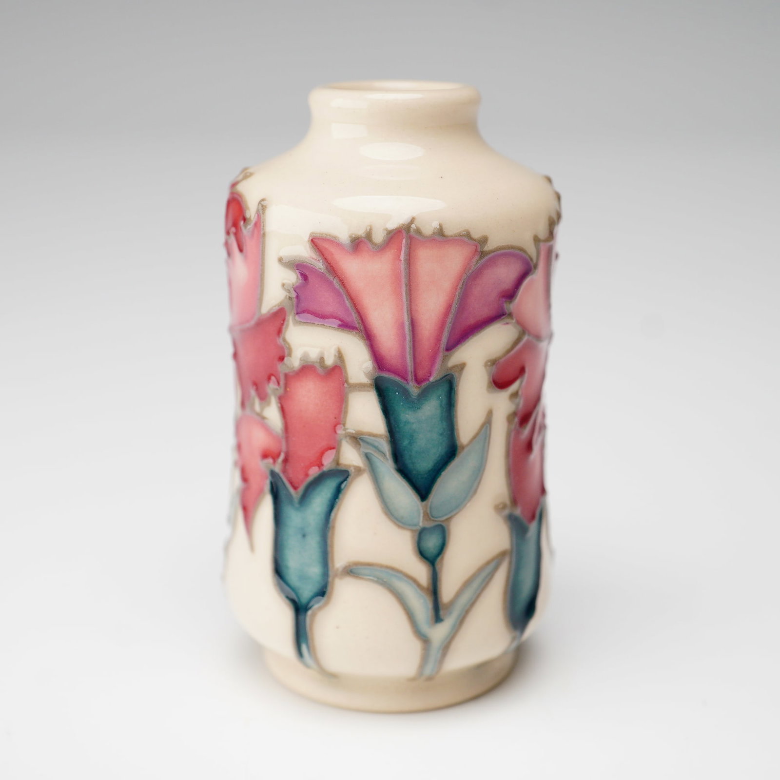 Moorcroft Miniature Floral Months of The Year Vase, Carnation: Moorcroft Miniature Floral Months of the Year vase for January, decorated with the carnation motif. The vase is crafted in cream ground with tube-lined decoration featuring stylized carnations in red,