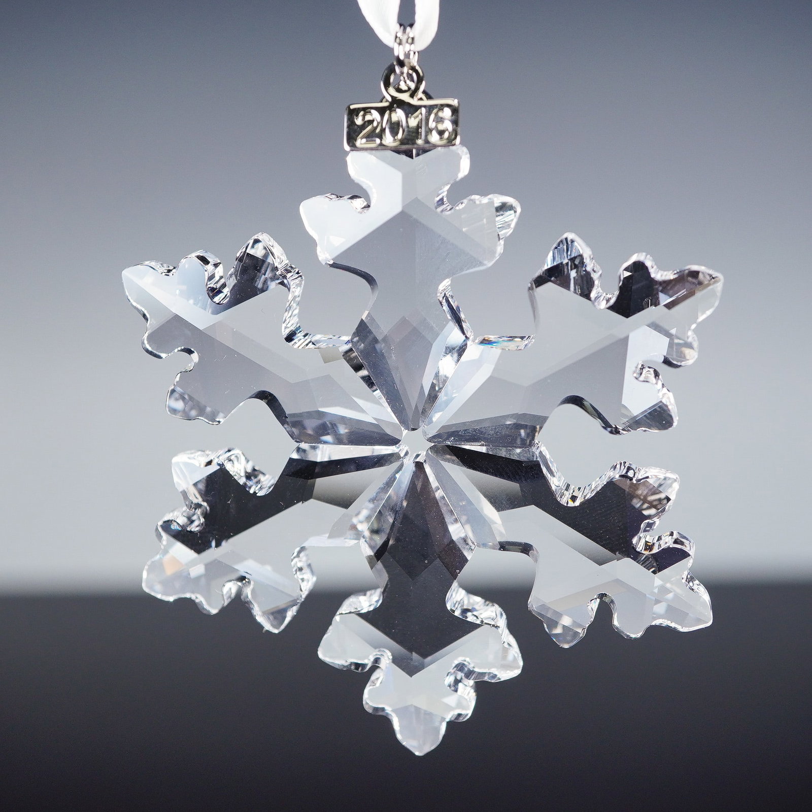 Swarovski Crystal 2016 Christmas Ornament: Celebrating the 25th year of the annual ornament tradition, this 2016 edition showcases a finely cut snowflake design sparkling in clear crystal. Designed by Verena Castelein, it is suspended from a w