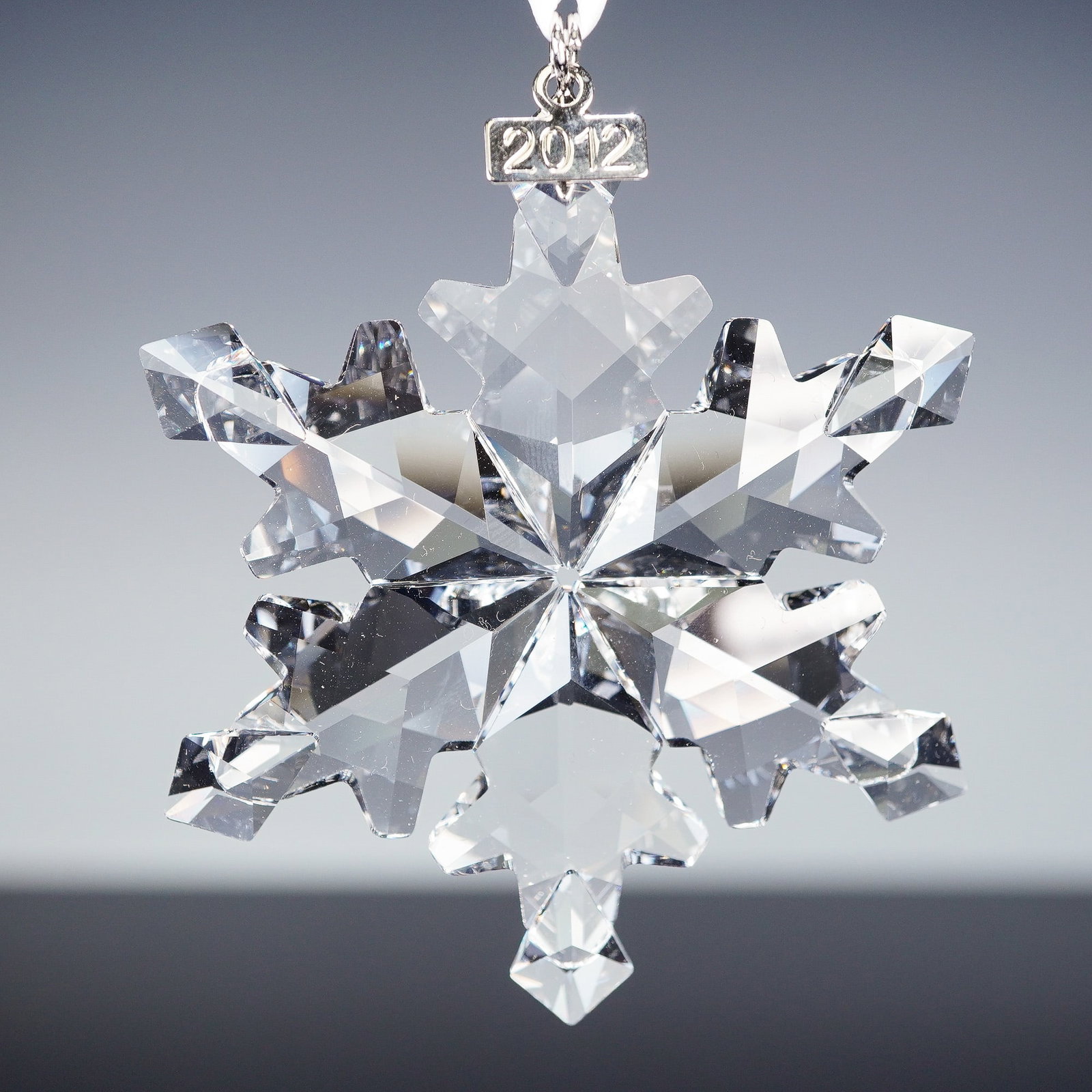 Swarovski Crystal Snowflake Ornament, Christmas 2012: A Swarovski crystal snowflake ornament from the annual Christmas series, dated 2012. Beautifully faceted to catch the light, this six-pointed snowflake is finished with a silver-tone metal tag engrave