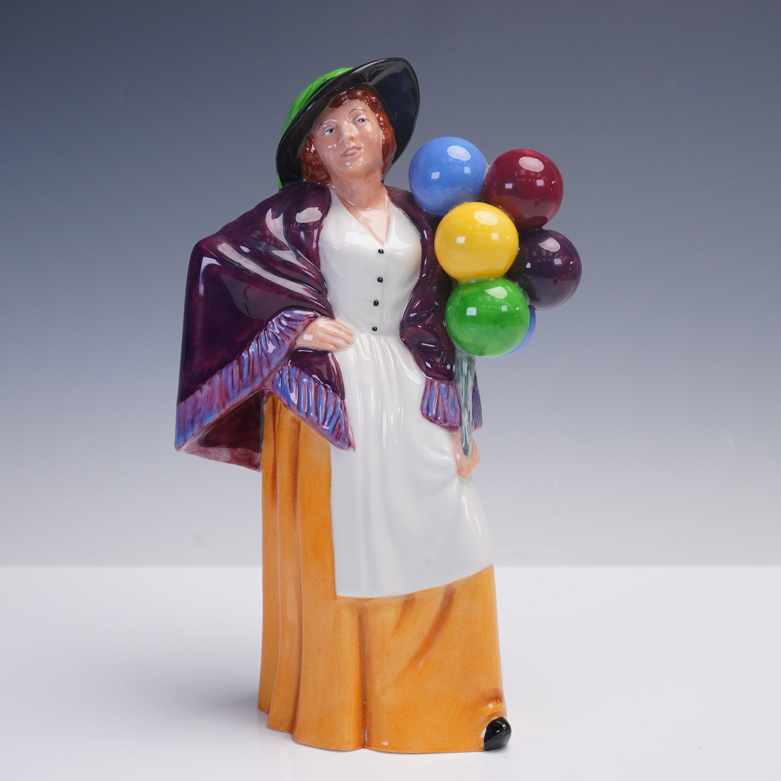 Royal Doulton Balloon Lady HN 2935 Figurine by Peter A. Gee: A charming Royal Doulton figure titled Balloon Lady, model HN 2935, hand-made and hand-decorated in England by Royal Doulton. Designed by Peter Gee and dated 1983, this collectible figure features a s