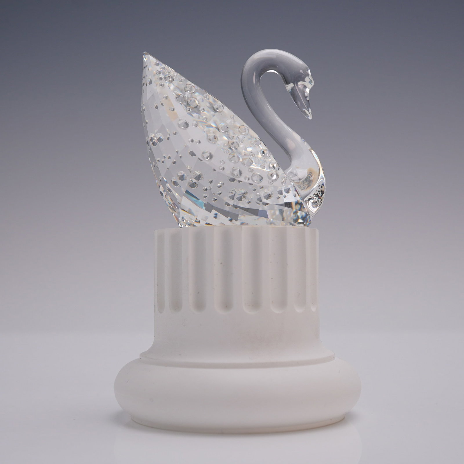 Swarovski Crystal 100th Anniversary Swan with Box and Stand: Swarovski crystal swan figurine issued in celebration of the company's 100th anniversary, 1895 to 1995. The swan features a smooth arched neck and a fully faceted body decorated with circular cuts tha