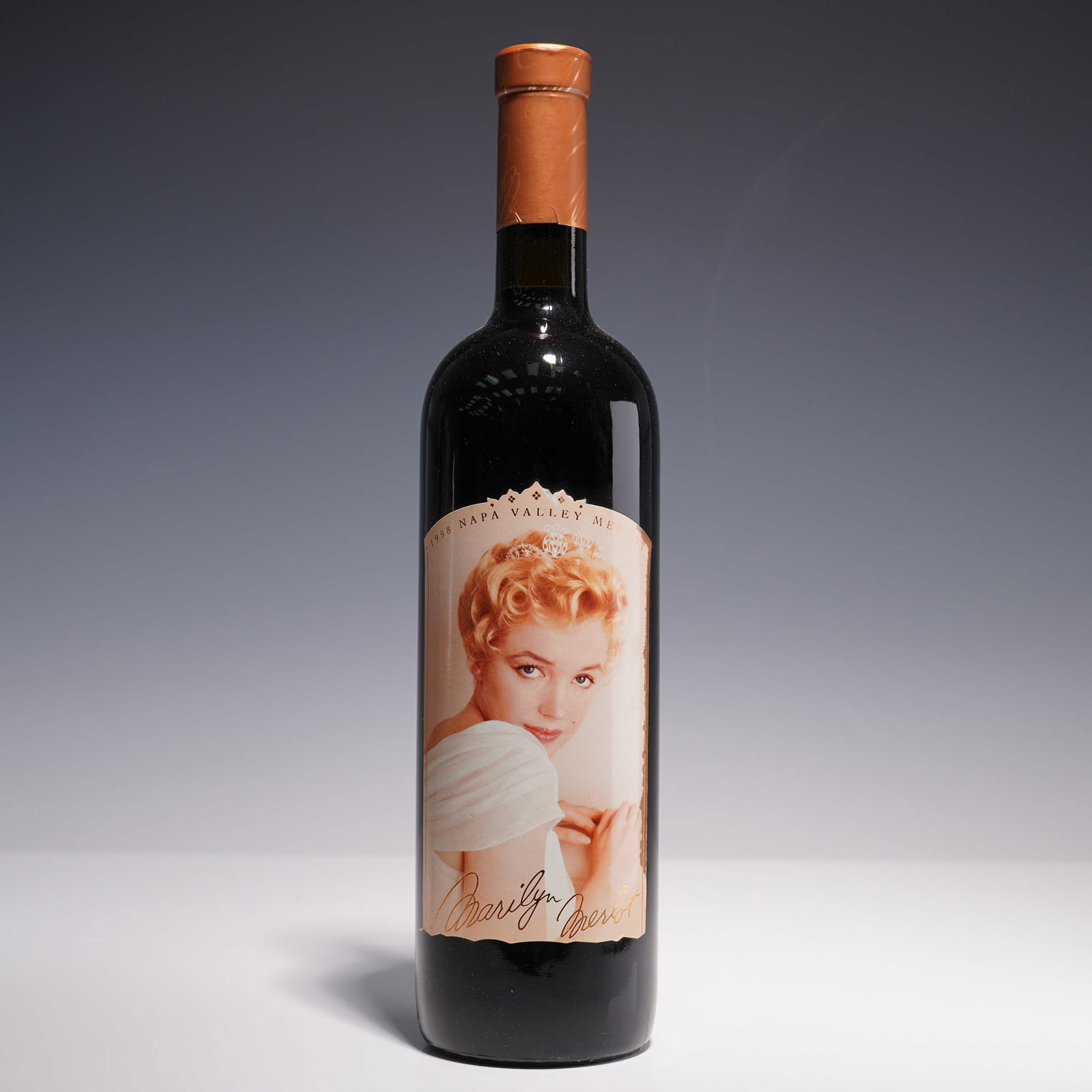 1998 Marilyn Monroe Merlot Napa Valley Wine: A 1998 vintage bottle of Marilyn Merlot from Napa Valley, featuring a softly lit portrait of Marilyn Monroe adorned in white with a jeweled tiara. This collectible 750ml bottle was produced and bottle