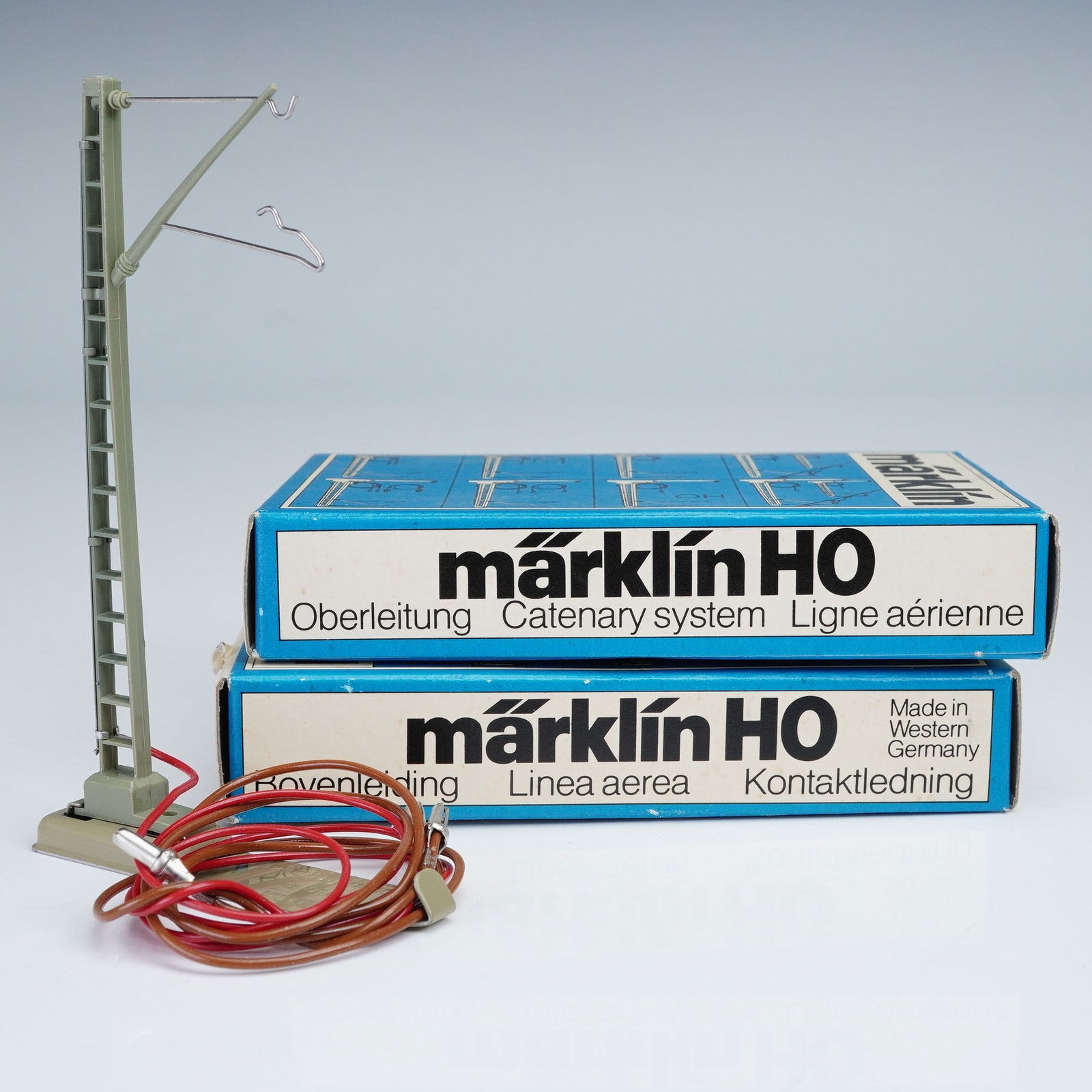 2pc Marklin Catenary System Parts, HO 7010: Marklin HO 7010 M catenary system components in original boxes. Each piece includes a green plastic mast with ladder detail, fitted with metal wire arms for overhead line support, and base embossed Ma