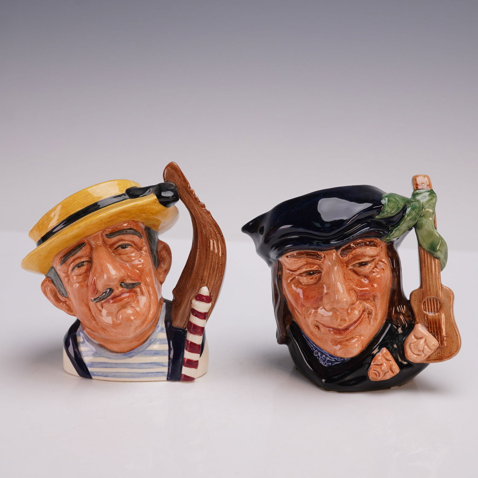 2pc Royal Doulton SM Character Jugs - Gondolier D6592 & Scaramouche D6561: Pair of Royal Doulton small character jugs, each hand-painted with fine detail and marked with Royal Doulton backstamps to the undersides. Includes Gondolier (D6592, designer: David B. Biggs, Characte