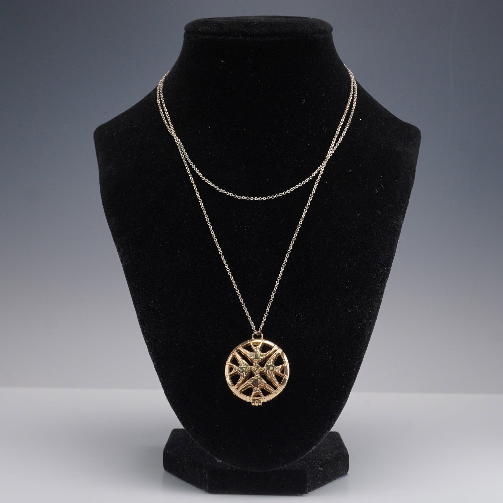 Lalique Hirondelles Perfume Pendant Diffuser Necklace: This Lalique Hirondelles perfume pendant diffuser features an elegant circular gold-tone design with four intricately detailed swallows in flight, arranged in a cross-like formation around a central p