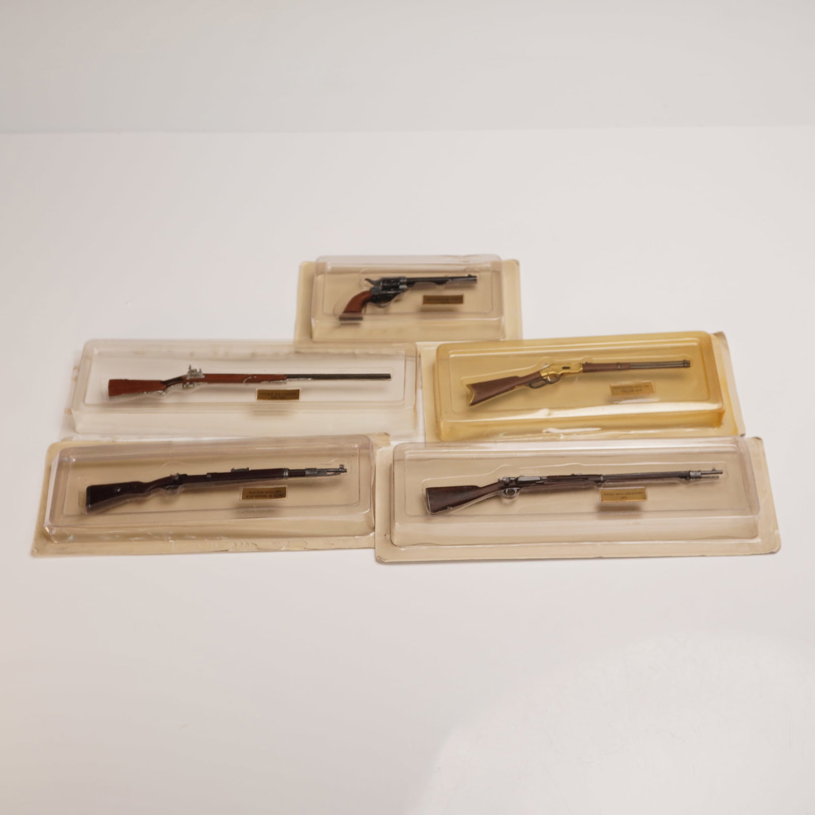 5pc Andrea Miniatures Firearms Collection: A group of five finely crafted miniature firearms by Andrea Miniatures, each presented in its original molded plastic casing with labeled brass plaques. The set includes iconic models such as the Revo