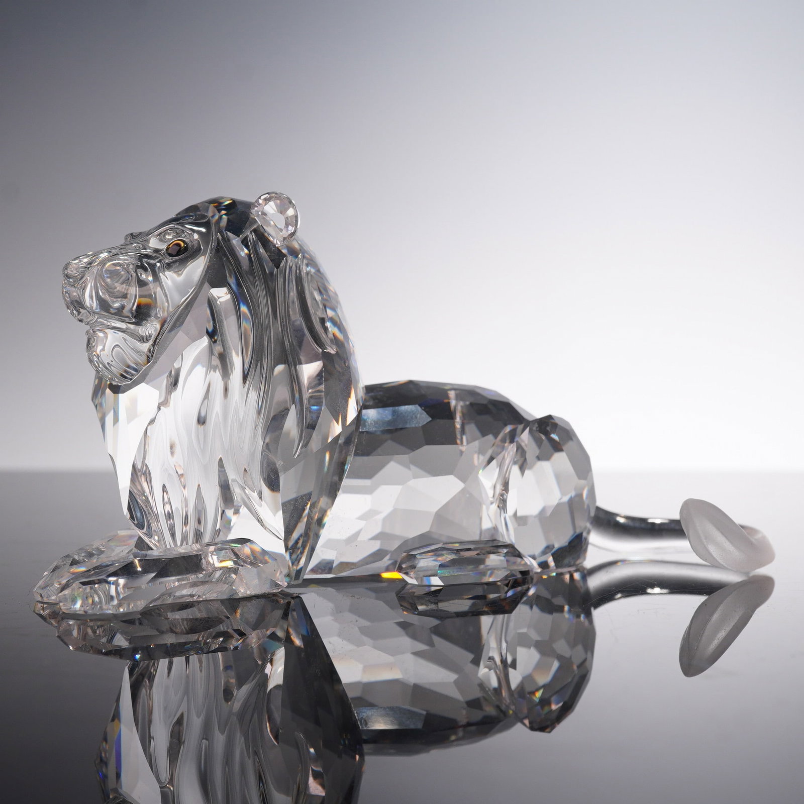 Swarovski Crystal Figurine, Inspiration Africa, Lion, 185410: This Swarovski Crystal figurine from the Inspiration Africa series, model number 185410, beautifully depicts the majestic lion in a seated position, exuding elegance and strength. Expertly crafted in 