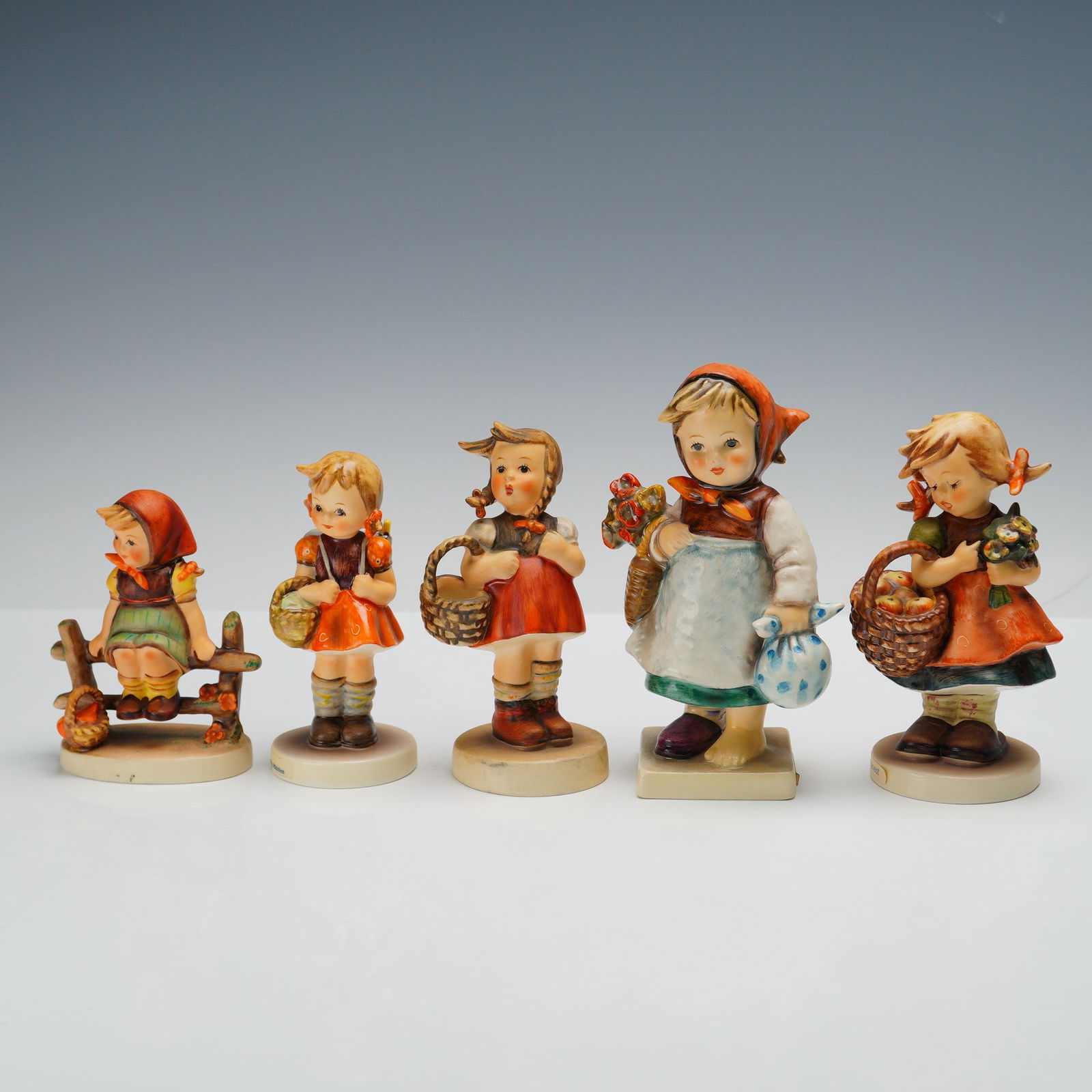 5pc Goebel Hummel Figurines: An enchanting group of 5 Goebel Hummel figurines is offered here, including School Girl with her satchel, and Wear Wanderer carrying both a basket and a small bundle. Autumn Harvest charms with a bask