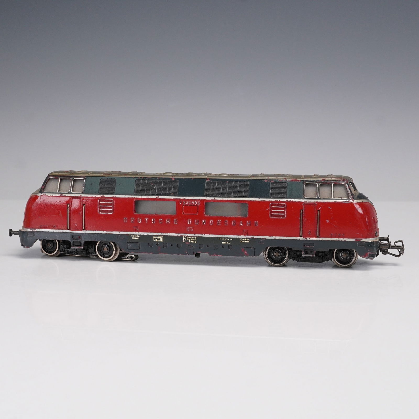 Marklin Collectible, Class V 200.0 Diesel Locomotive: It is finished in red with a gray roof and carries the Deutsche Bundesbahn markings along the body, with the road number V200006 displayed at both ends. The locomotive features detailed molded vents,