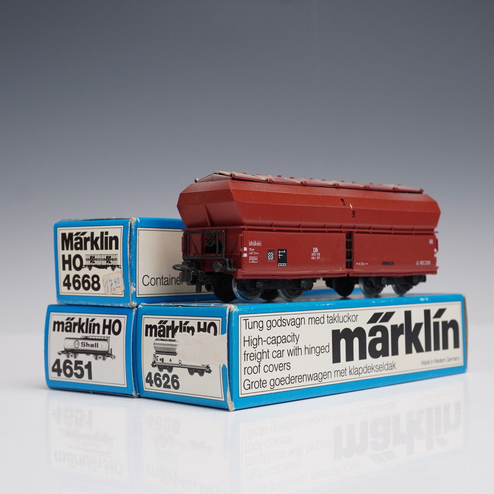 3pc Marklin HO German Model Train Cars: Group of three Marklin HO scale model train cars with original boxes. The collection includes one yellow Shell A.G. Hamburg tank car with Shell branding; one red high-capacity freight car with hinged