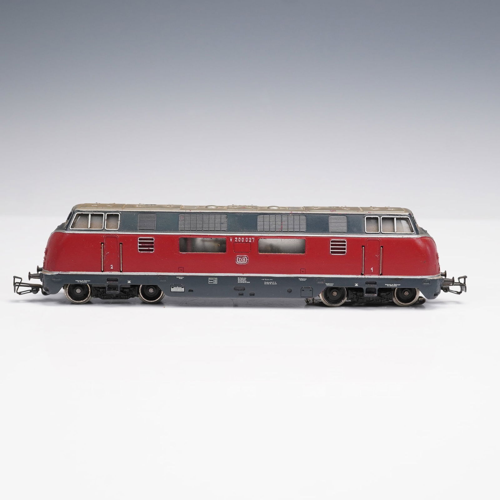 Vintage Marklin HO 3921 V200-027 Diesel Locomotive: Marklin HO gauge German diesel locomotive, model V200 027, finished in red and grey Deutsche Bundesbahn livery with molded detailing and factory markings. The underside is embossed with Marklin, retai