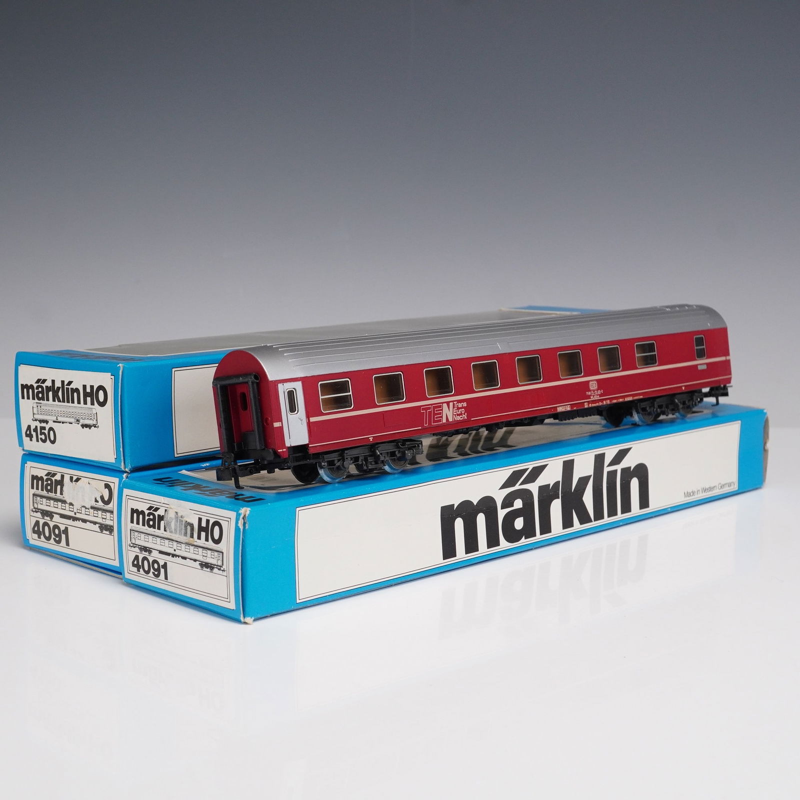 3pc Marklin HO Passenger Coaches: Collection of three Marklin HO scale passenger coaches, including model no. 4150 in red and silver TEN livery, model no. 4091 in red with silver roof, and a cream and blue DB 1st class coach. Each car