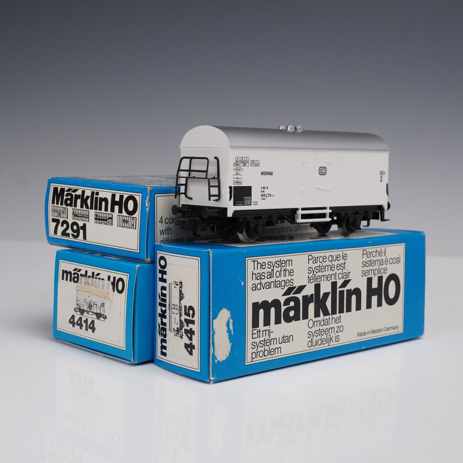 3pc Marklin HO German Model Train Cars and Containers: The collection includes one yellow freight car marked "Ecuador Bananas" with original box labeled Marklin 4414, featuring side graphics of a man holding bananas. Also included are two white and silver