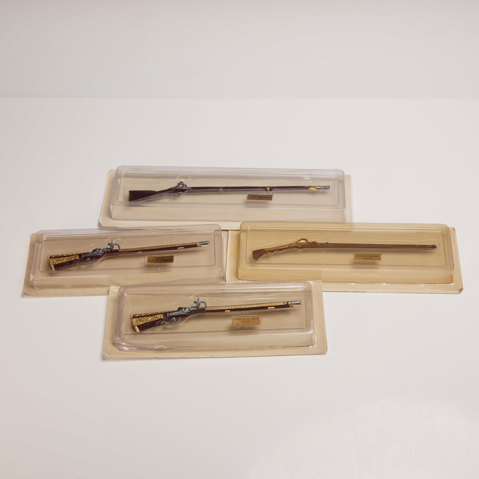 4pc Andrea Miniature Historical Rifle Model Collection: A group of four collectible model rifles by Andrea Miniatures, each housed in its original molded plastic casing with labeled brass plaques. The models represent historically significant firearms, inc