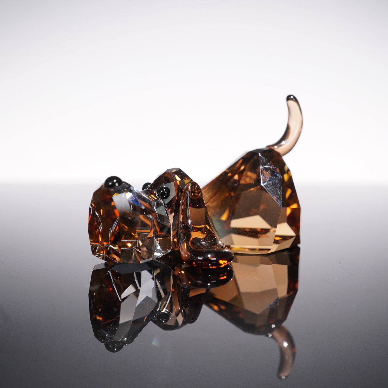 Swarovski Crystal Figurine, Lovlots Basset Hound Peppino: Peppino the basset hound from Swarovski's Lovlots Gang of Dogs is crafted in faceted Light Smoked Topaz crystal, with a clear crystal snout and expressive Jet crystal eyes. The design captures the gen