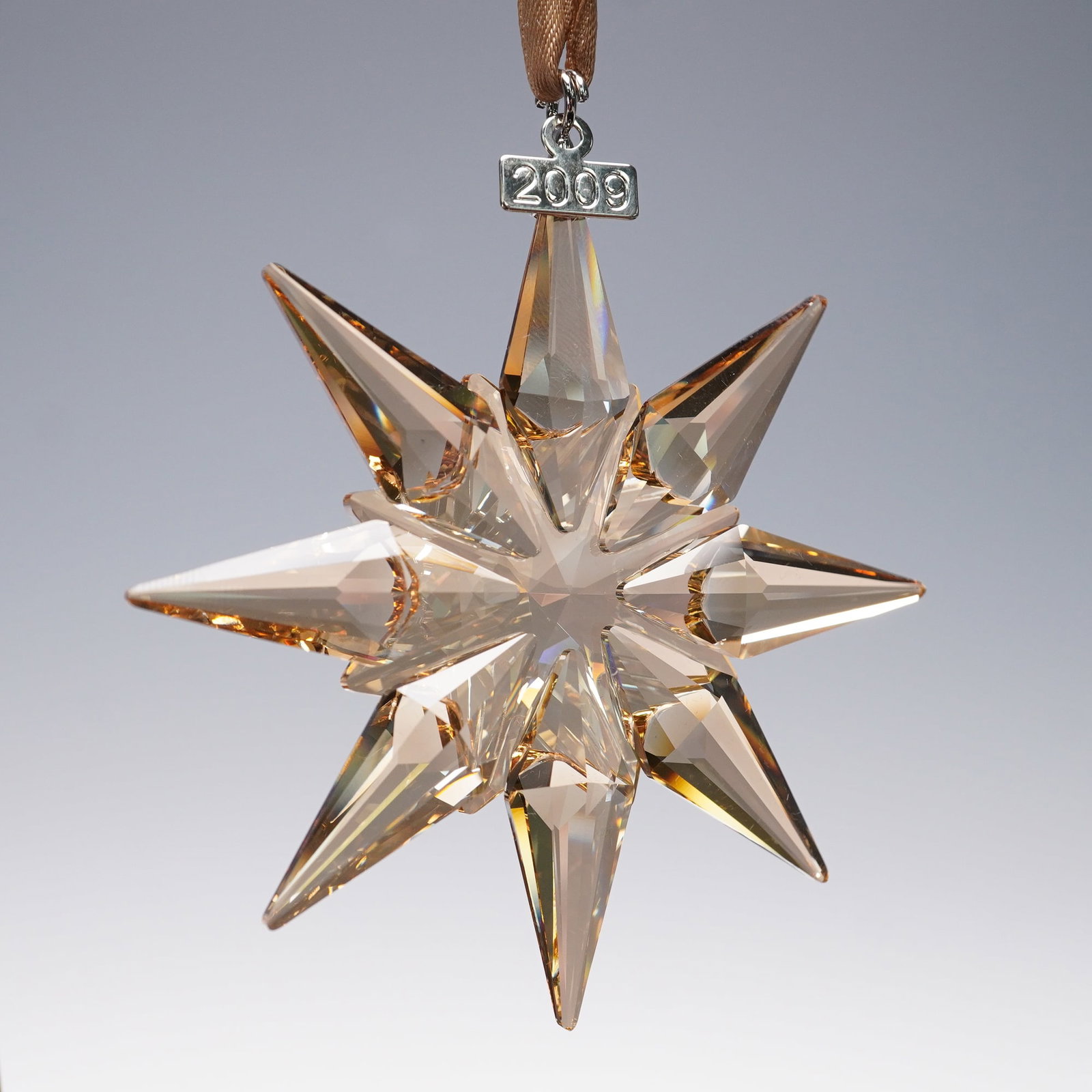 Swarovski Crystal Ornament, 2009 Christmas Ornament Gold SCS 1026761: This limited-edition piece features a striking 12-pointed star design crafted in golden crystal, suspended from a brown satin ribbon with a silver-tone metal tag engraved 2009. The ornament comes hous