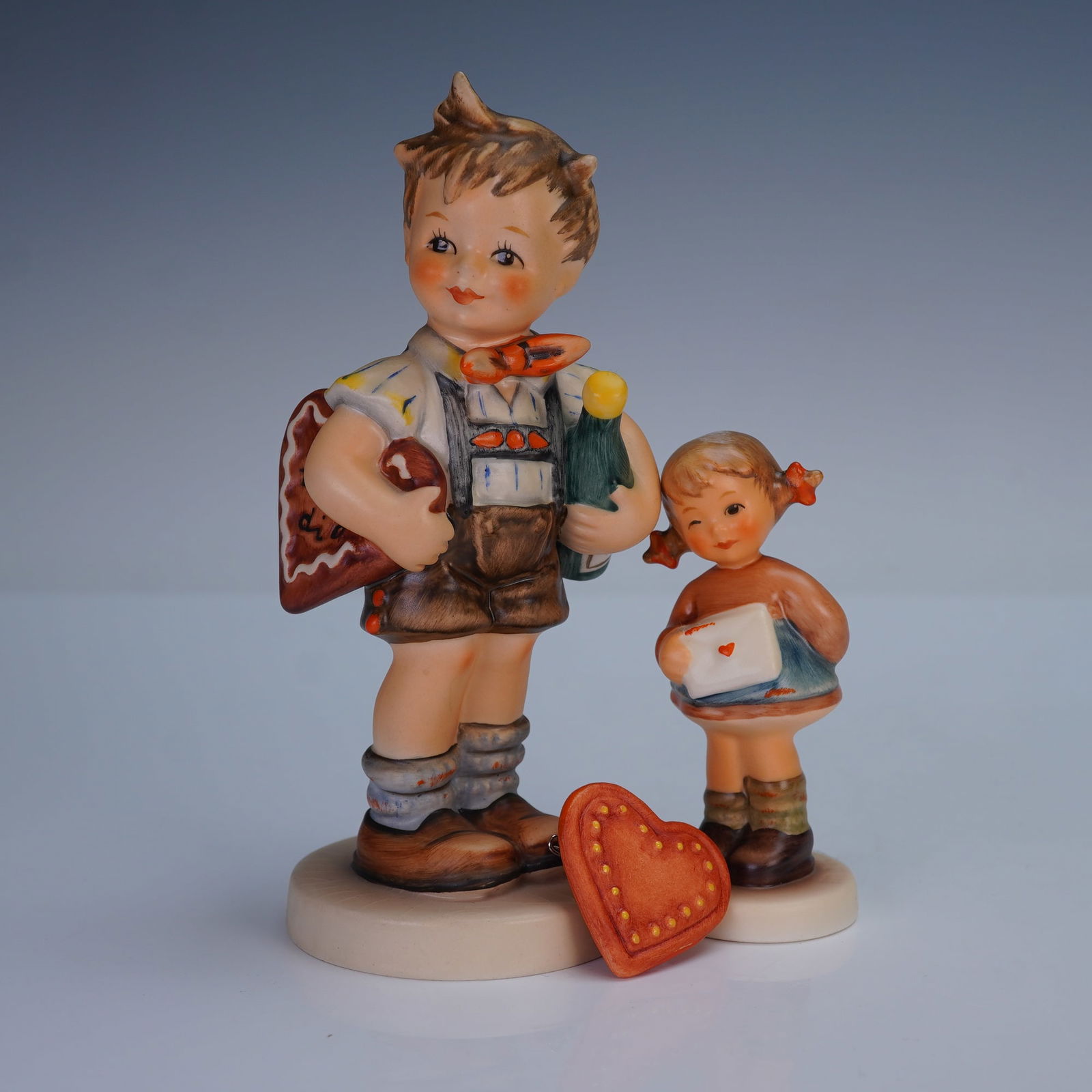 3pc Goebel Hummel Heart Theme Figurines and Pin: A lovely 3 piece Goebel Hummel lot centered around a heart and love theme, including two porcelain figurines and one matching pin. The first figurine is the Exclusive Special Edition No.4 issued in 19