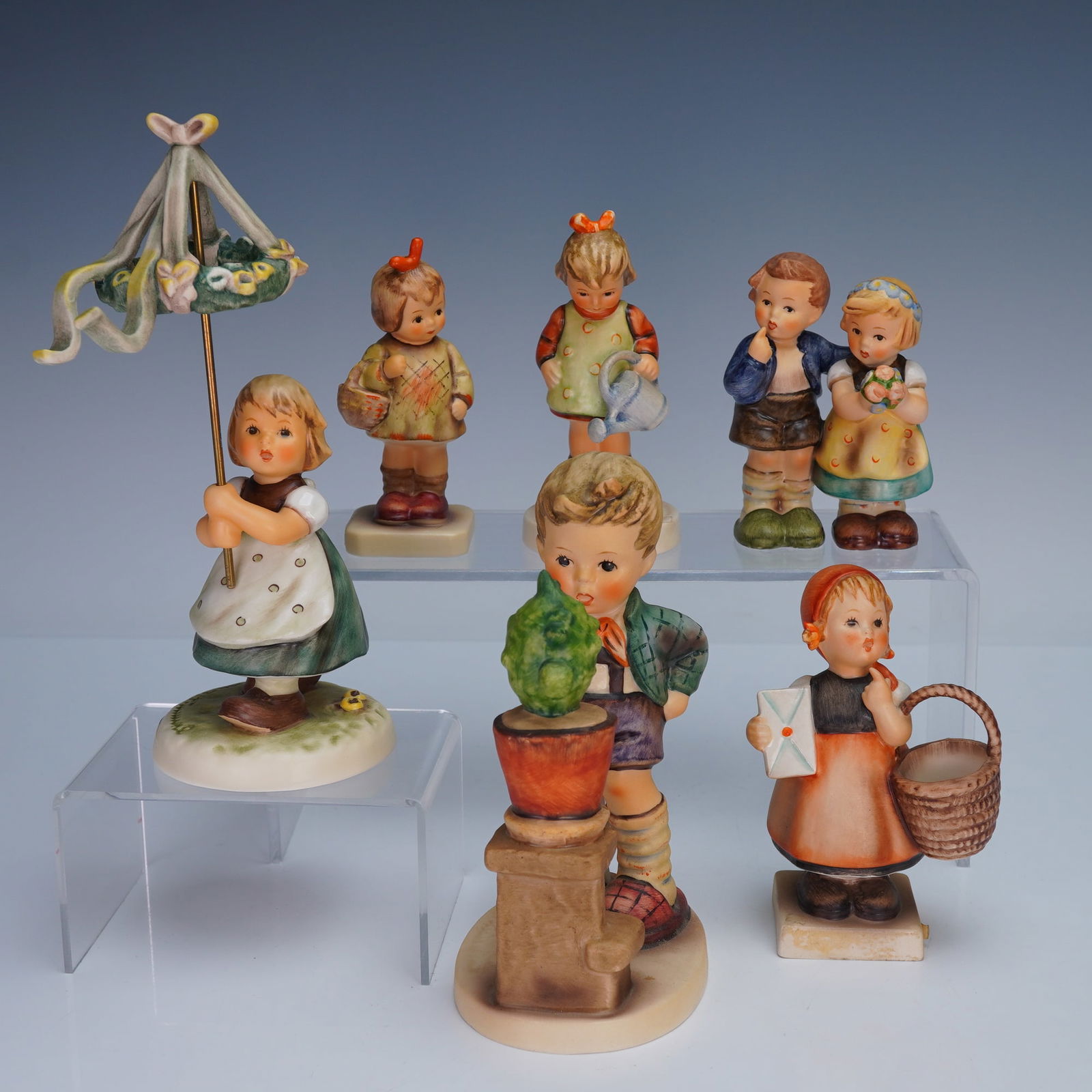 6pc Goebel Hummel Figurines: Collection of six Goebel Hummel figurines, each hand painted and modeled as children in various charming scenes. Includes girl with maypole, girl with basket and letter, boy with potted plant, girl wi