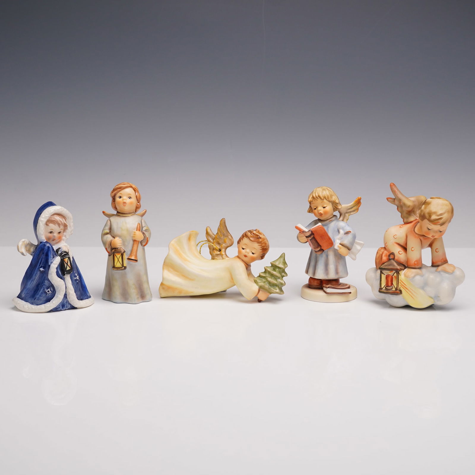 5pc Goebel Hummel Angel Figurines, Seraphim Soprano and More: Five angel figurines, each hand-painted and marked Goebel W. Germany on the base. The group includes: Angel with a lantern, a blue-cloaked angel holding a lantern, Hosanna, a standing angel in a pale