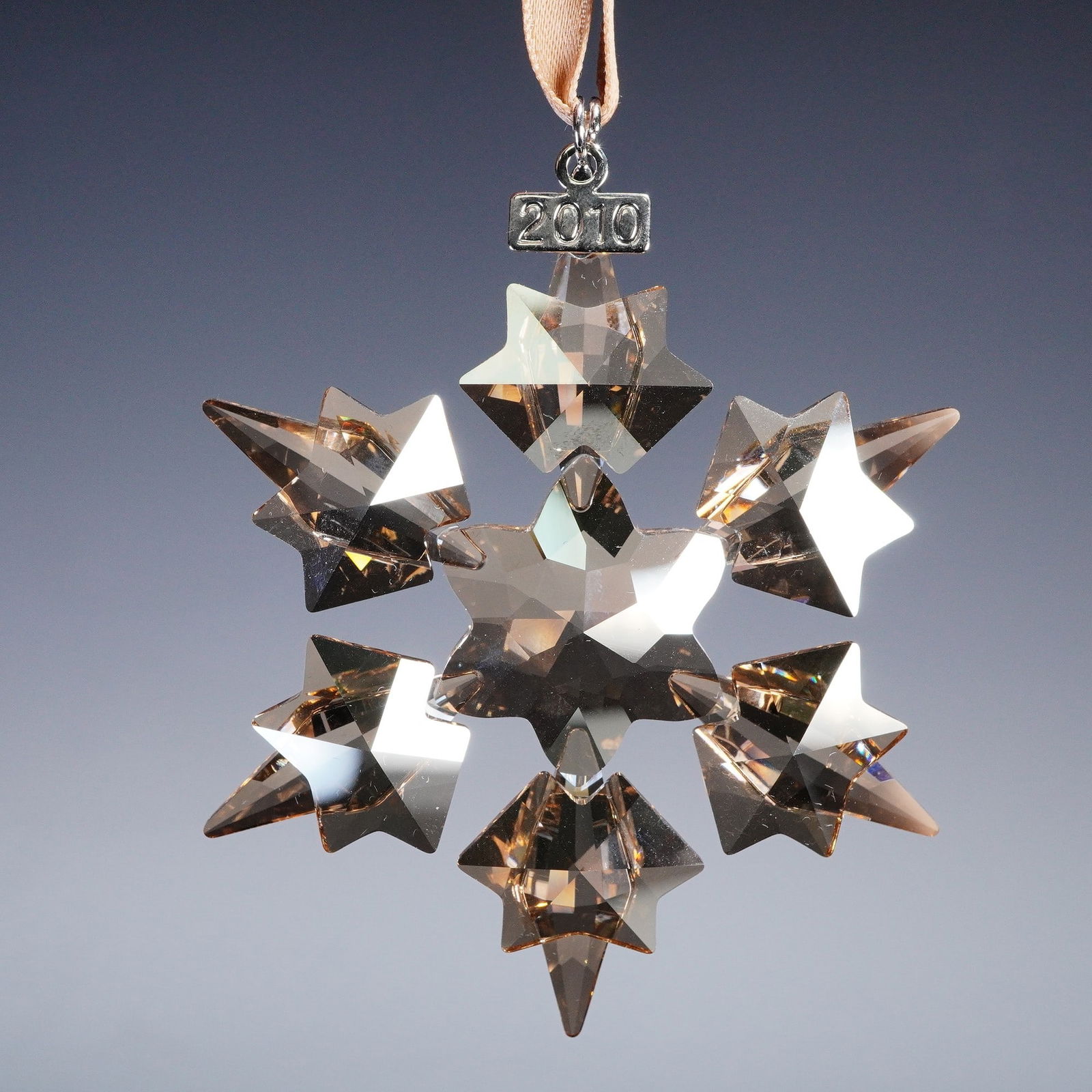 Swarovski Crystal Christmas Ornament 2010 SCS Annual Edition: Swarovski crystal Christmas ornament 1054560 SCS Annual Edition 2010. This unique design features a clear crystal star snowflake with a warm golden hue, suspended from a golden ribbon with a silver to