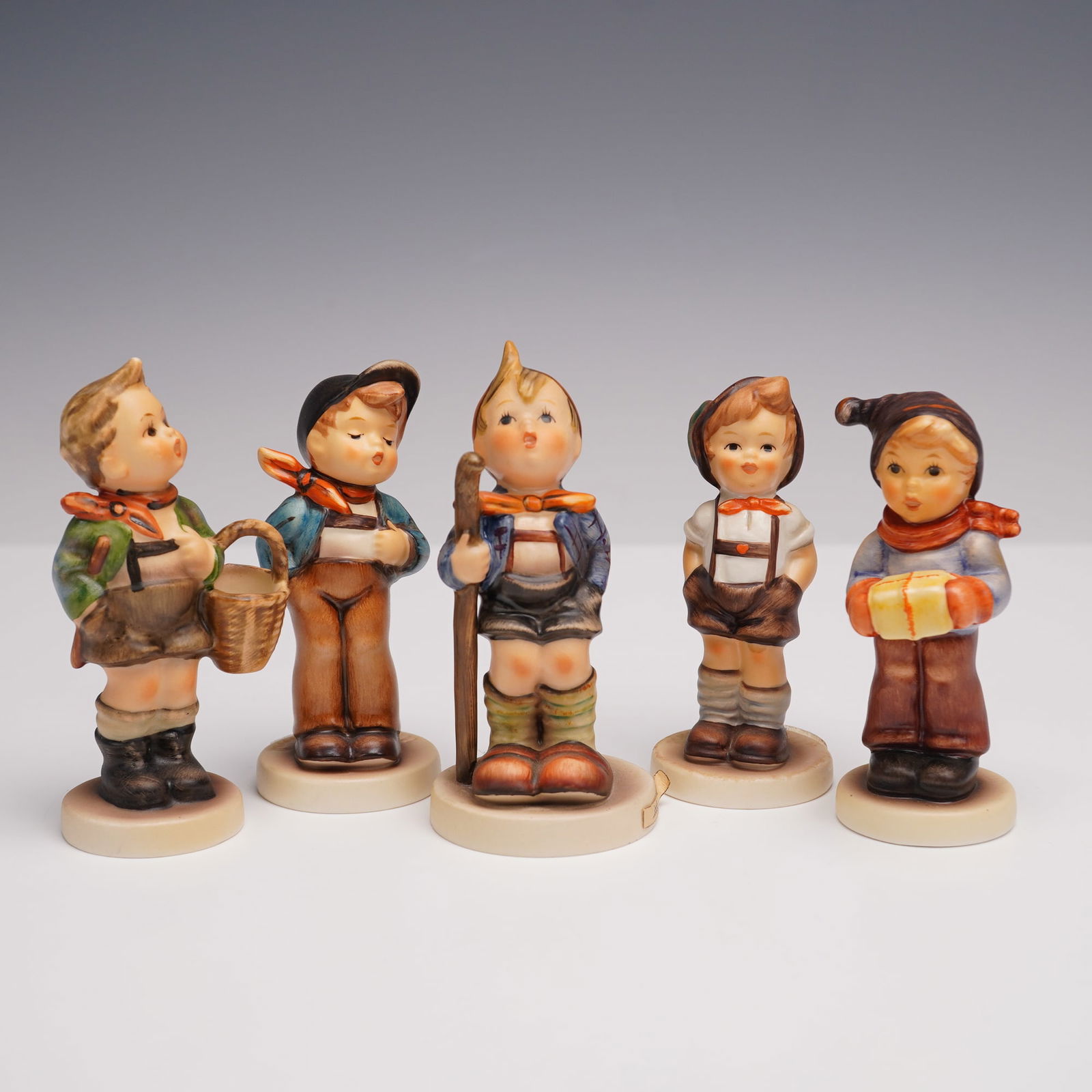 5pc Goebel Hummel Boyhood Memories Figurines: Five hand-painted porcelain pieces, each depicting a charming young boy in traditional Bavarian-style attire. Included are: Lucky Fellow (Ein frohlicher Gesell), For Keeps (Jungbauer), For Me? (Nur ne