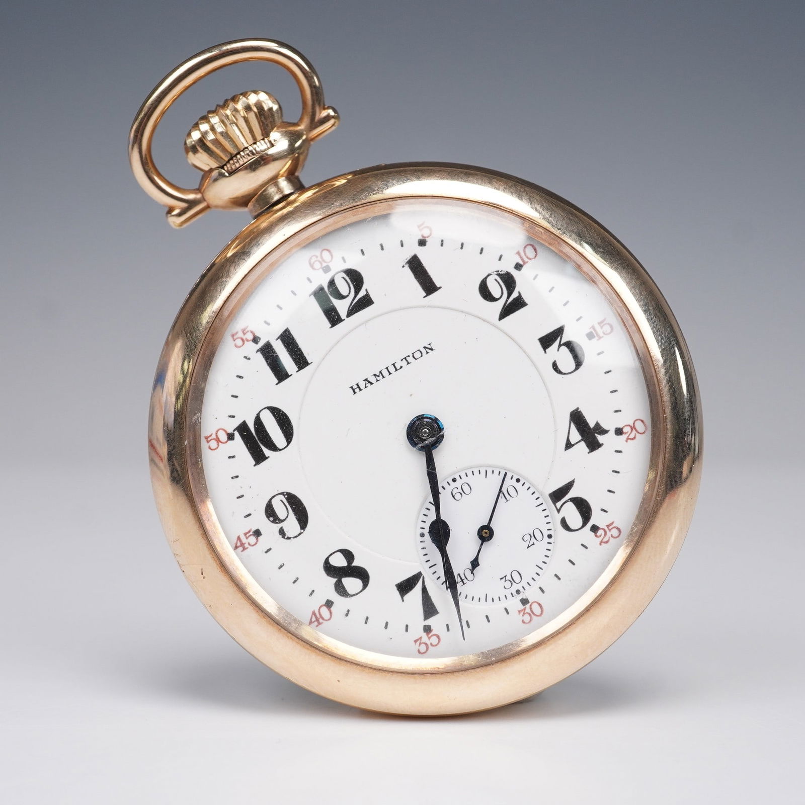Hamilton Watch Co. 922 16S LS Royal 25 Year Gold Filled Pocket Watch: Features a tilt-out movement design. The dial is marked "Hamilton" and includes bold black Arabic numerals for hours, with red Arabic numerals for the outer minute track in increments of five. The sub