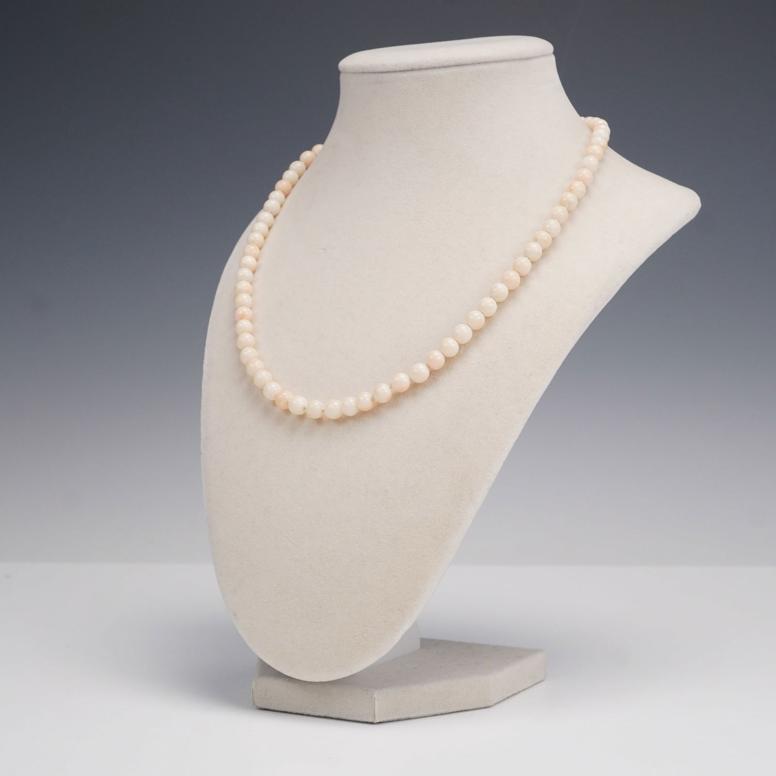 Angel Skin Coral Bead Necklace: A delicate necklace composed of round Angel Skin Coral beads displaying a soft palette of blush pink, peach, and cream tones. The beads are hand-knotted for strength and smooth drape, and the strand i