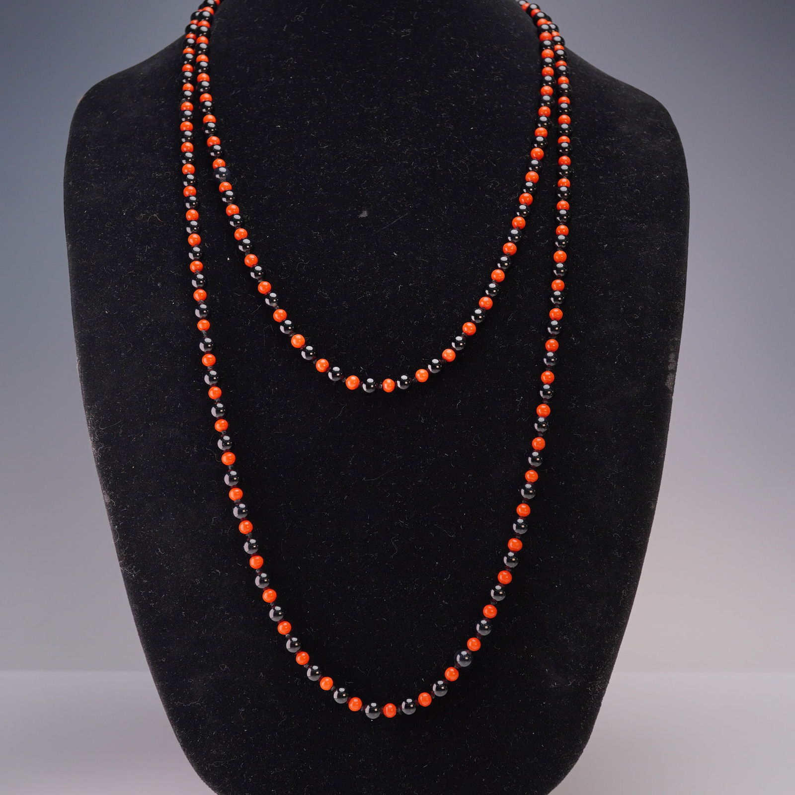 Onyx and Carnelian Beaded Necklace with 14K Gold Clasp: Elegant long strand necklace featuring alternating polished black onyx and vibrant red carnelian beads, each individually knotted for durability and fluid drape.The necklace is secured with a stamped