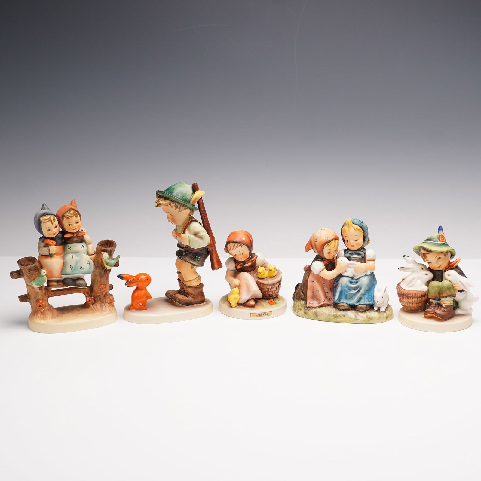 5pc Goebel Hummel Animal Pal Themed Figurines: This delightful lot includes five charming Goebel Hummel figurines full of playful character and vibrant color. Coquettes depicts two girls seated together on a rustic fence with two little birds perc