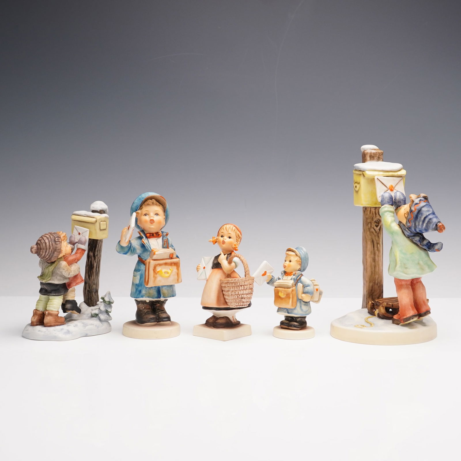 5pc Goebel Hummel Mail Themed Figurines: This lot features five Goebel Hummel figurines themed around letters and mail with delightful detail. Meditation shows a young girl in an apron holding a basket and a letter. Postman appears in two ve