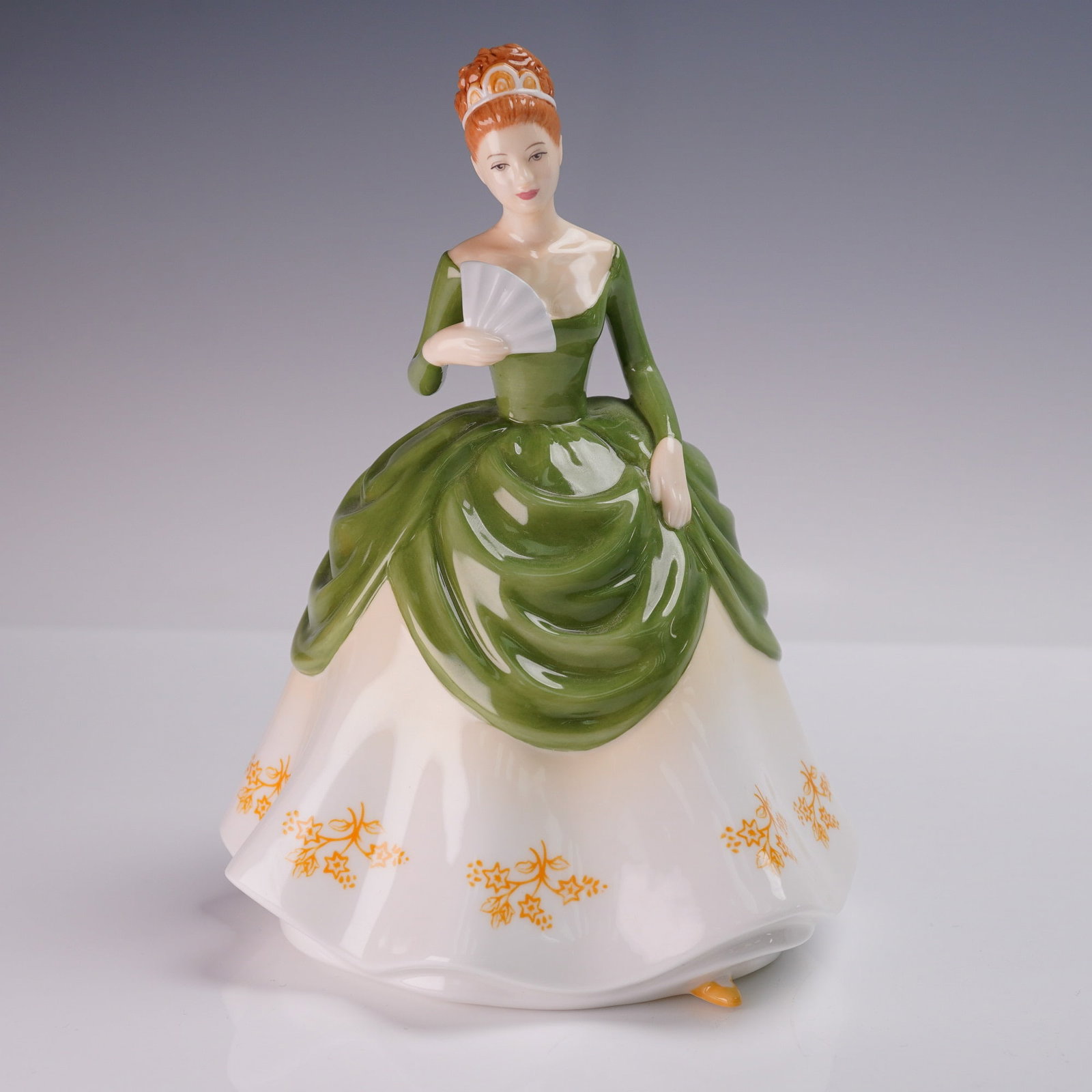 Royal Doulton Figurine, Soiree HN4864: A bone china figurine from the Pretty Ladies collection. This hand-made and hand-decorated piece depicts a red-haired lady in a green bodice and over-skirt with a white underskirt decorated with yello