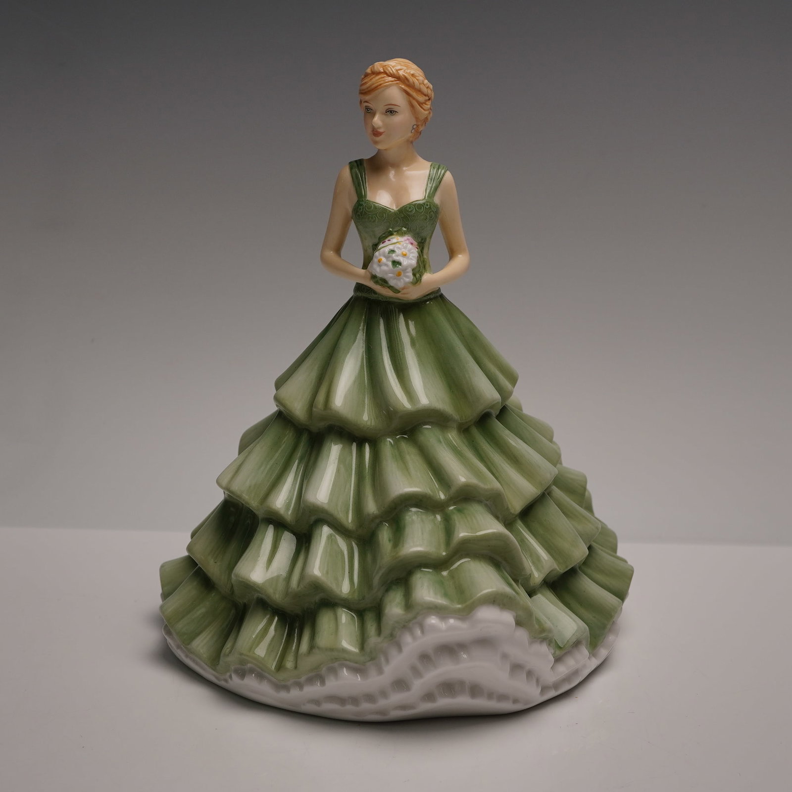 Royal Doulton Sentiment Petites Figurine, Cherished Moments HN5823: A Royal Doulton Sentiment Petites figurine titled Cherished Moments, model number HN5823. Designed by Neil Faulkner, this hand-decorated bone china piece depicts a young woman holding a small floral b