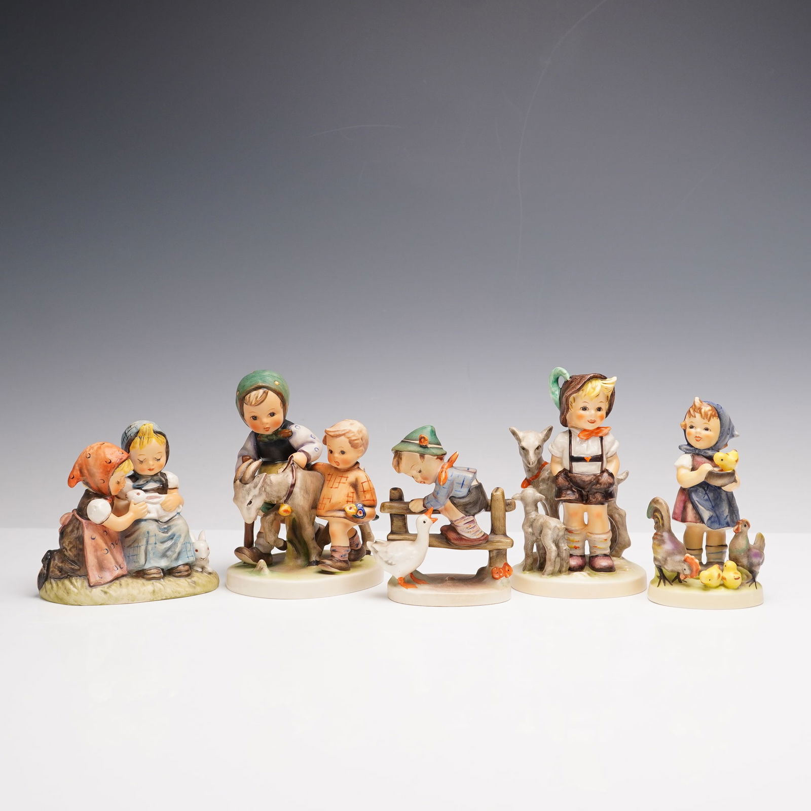 5pc Goebel Hummel Barn Themed Figurines: This charming group of five Goebel Hummel figurines captures delightful childhood scenes with vibrant detail and warmth. Feeding Time shows a sweet young girl caring for her rooster, chicken, and chic