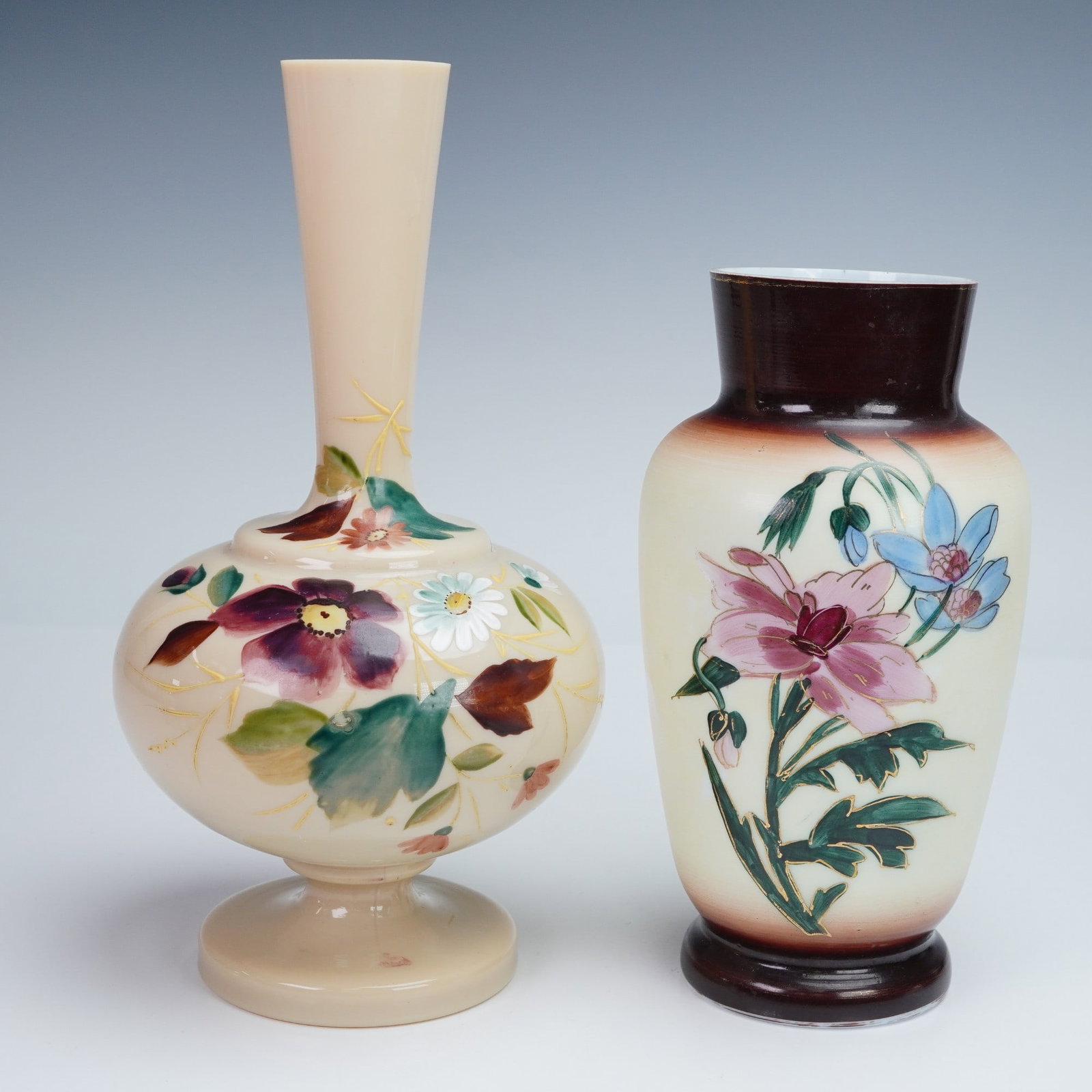 2pc Victorian Hand Painted Bristol Glass Vases: A pair of Victorian Bristol glass vases, each with a cream body hand painted with polychrome floral decoration. One of baluster form with a slender cylindrical neck on a spreading foot, the other of t