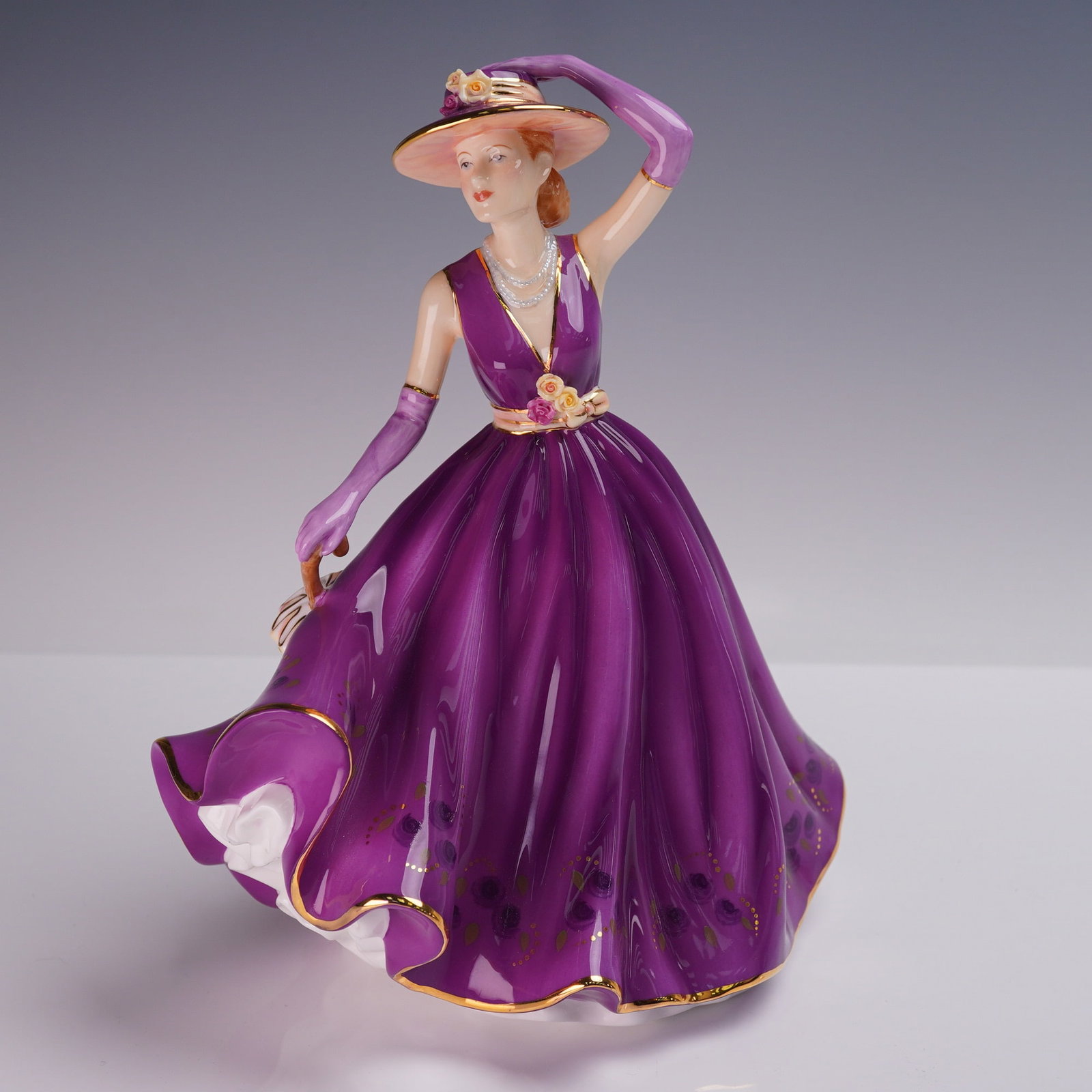 Royal Doulton Figurine, Emma HN5426: A Royal Doulton bone china figurine titled Emma, model HN5426, designed by Neil Faulkner and issued in 2008. The stylish figure is presented in a rich purple gown with floral hem detail, gold accents,