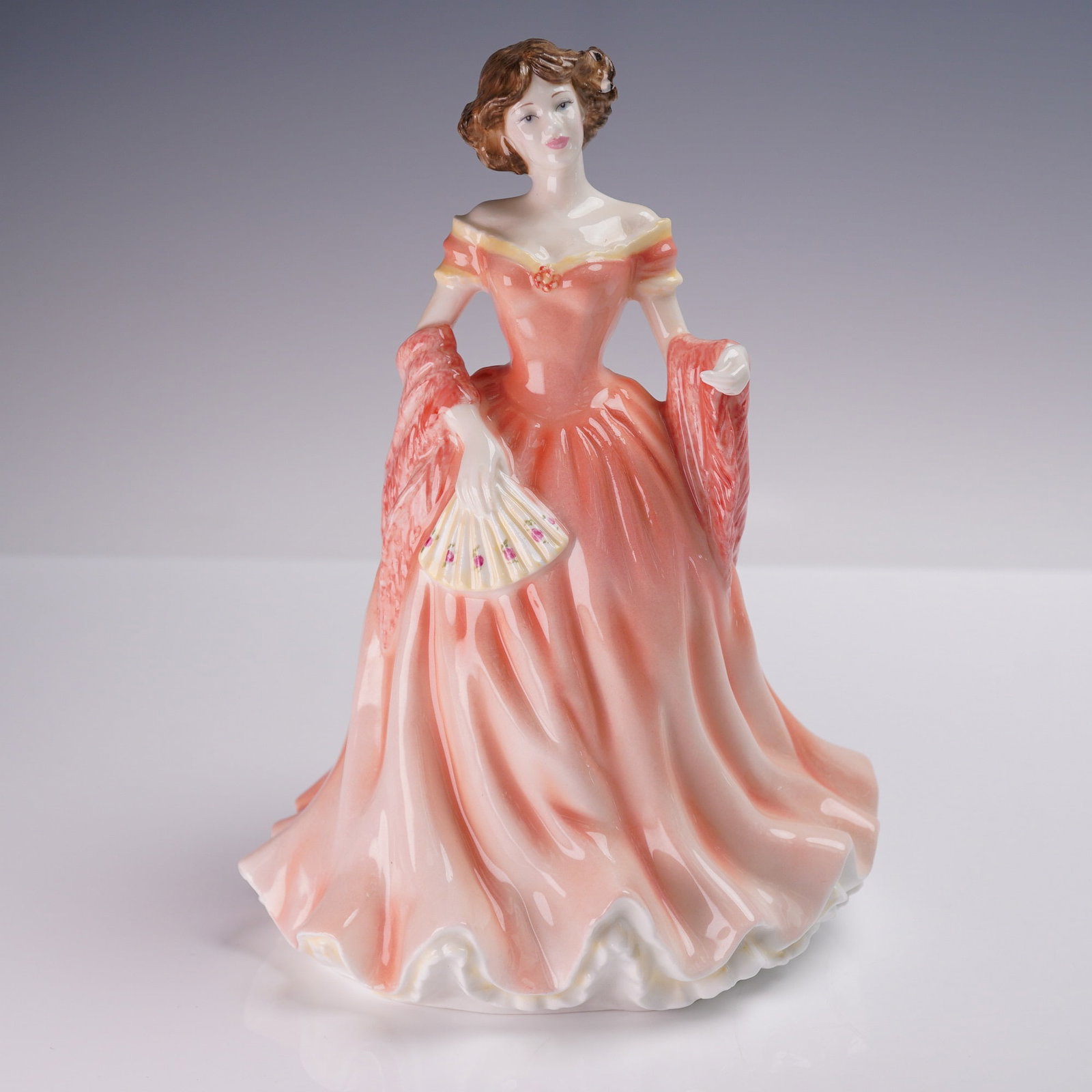 Royal Doulton Figurine, Ruth HN4099: Charming Royal Doulton bone china figurine titled Ruth, HN4099, modeled by Nada M. Pedley and issued in 1998. This elegant figure depicts a graceful lady in an off-the-shoulder coral pink gown, holdin