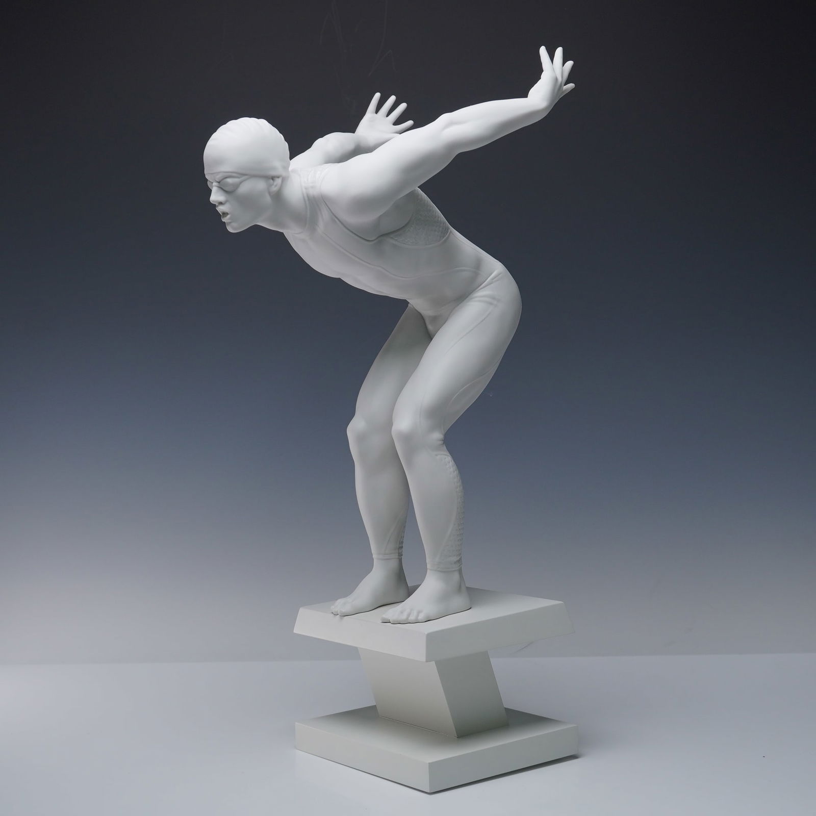 Lladro Porcelain Figurine, Swimmer 1008398: A striking Lladro porcelain figurine titled Swimmer, model 1008398. The athlete is depicted in the tense starting position, arms extended behind to propel forward, with every muscle defined to convey